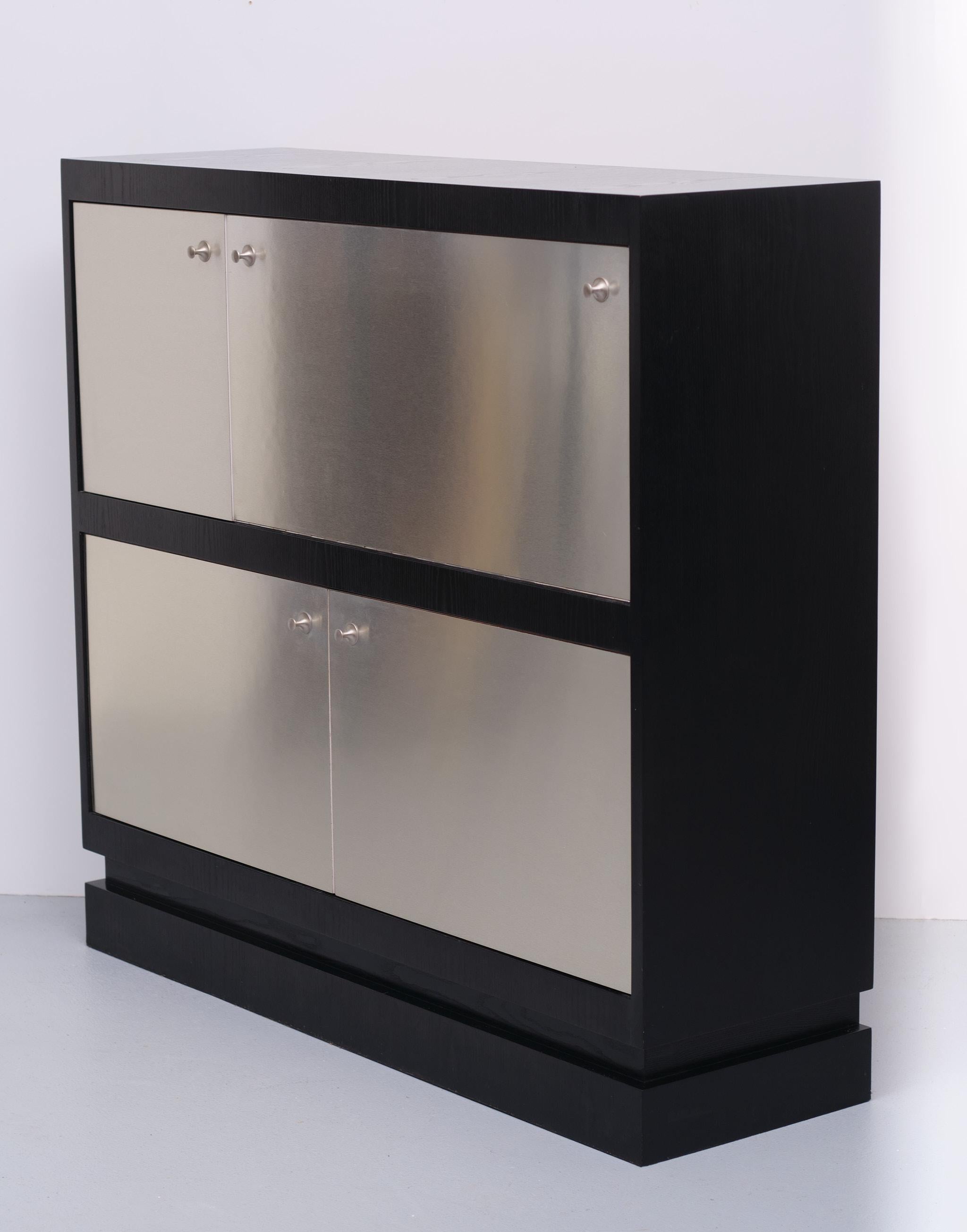 Gorgeous bar cabinet straight Brutalist lines. Gloss Aluminum front door panels.
Black ebonized frame, Inside room for your bottles and glasses. Mirrors and 
lighting. Typical Mad Men 1970s. Very good condition.
 