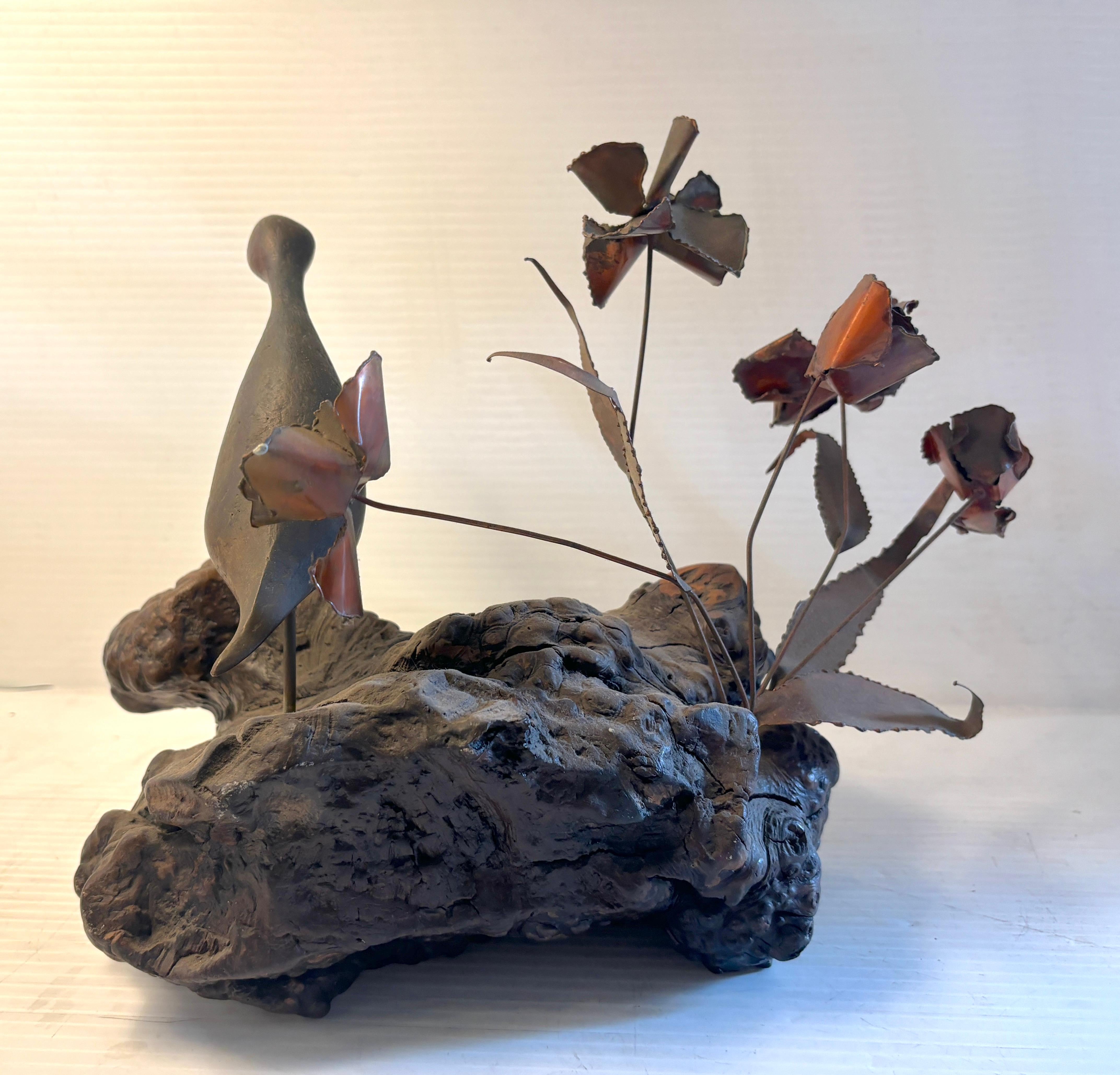 Holen Sie sich den Charme und die Laune des brutalistischen Dekors der Jahrhundertmitte nach Hause mit dieser attraktiven Statue eines kleinen Vogels mit Blumen. Sie ist aus Wurzelholz und Metall gefertigt und zeigt einen geschnitzten Jungvogel