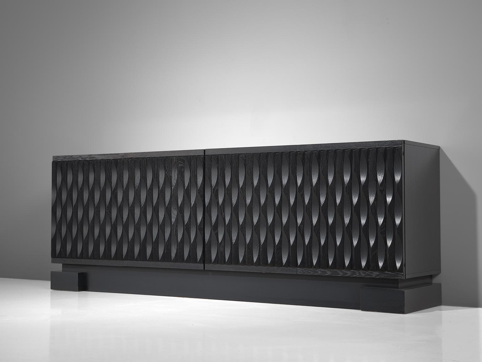 Brutalist black credenza, oak, Belgium, 1970s. 

Sturdy sideboard in oak with a black finish. Four door panels, each with a exceptional and very graphic, three-dimensional pattern. The continuous pattern gives this piece a very strong expression,
