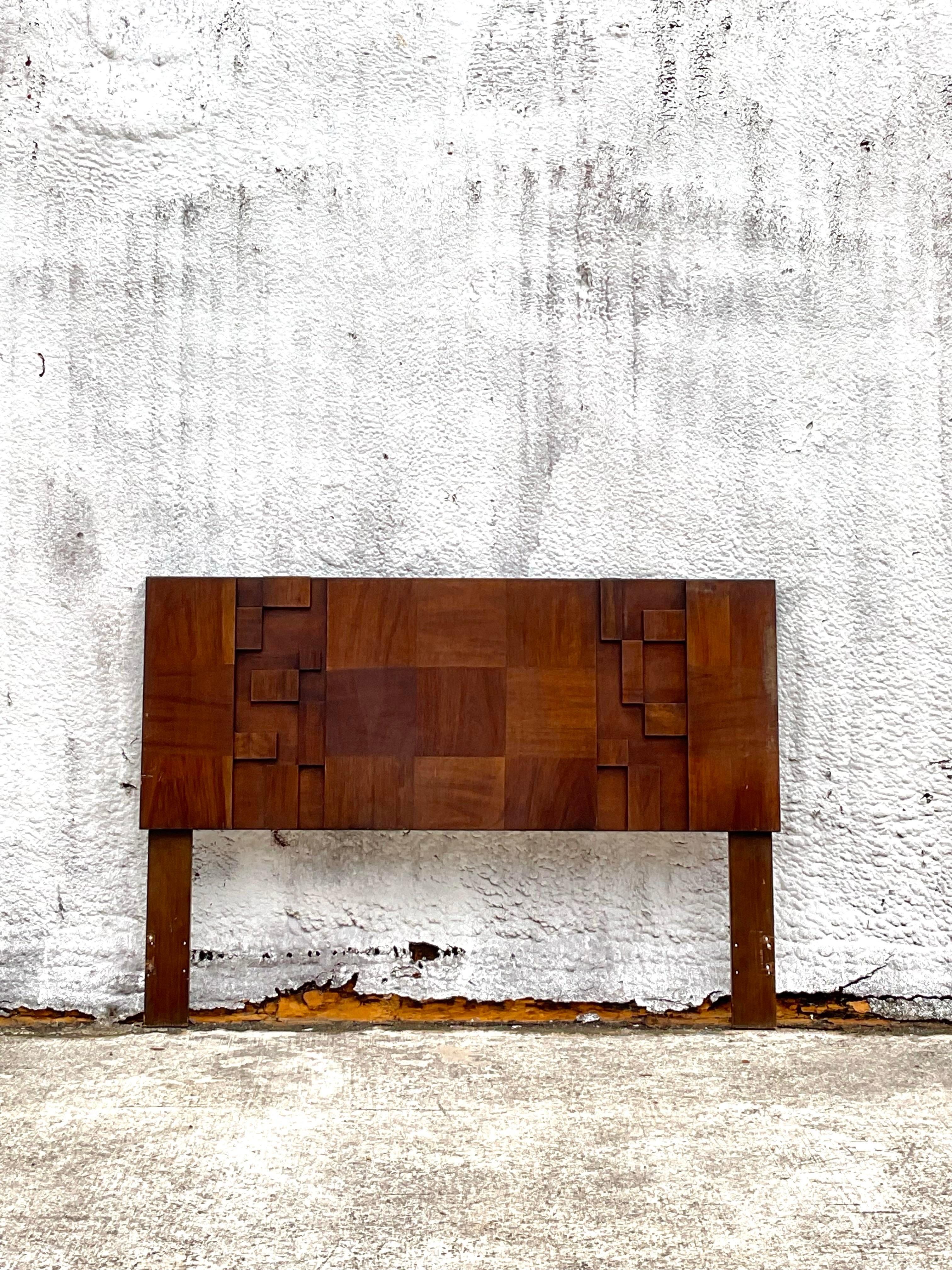 A lovely vintage headboard made of wood with intricate brutalist block design. Its geometric details make it seem modern which makes it a perfect addition to your bedroom. Acquired at a Palm Beach estate.