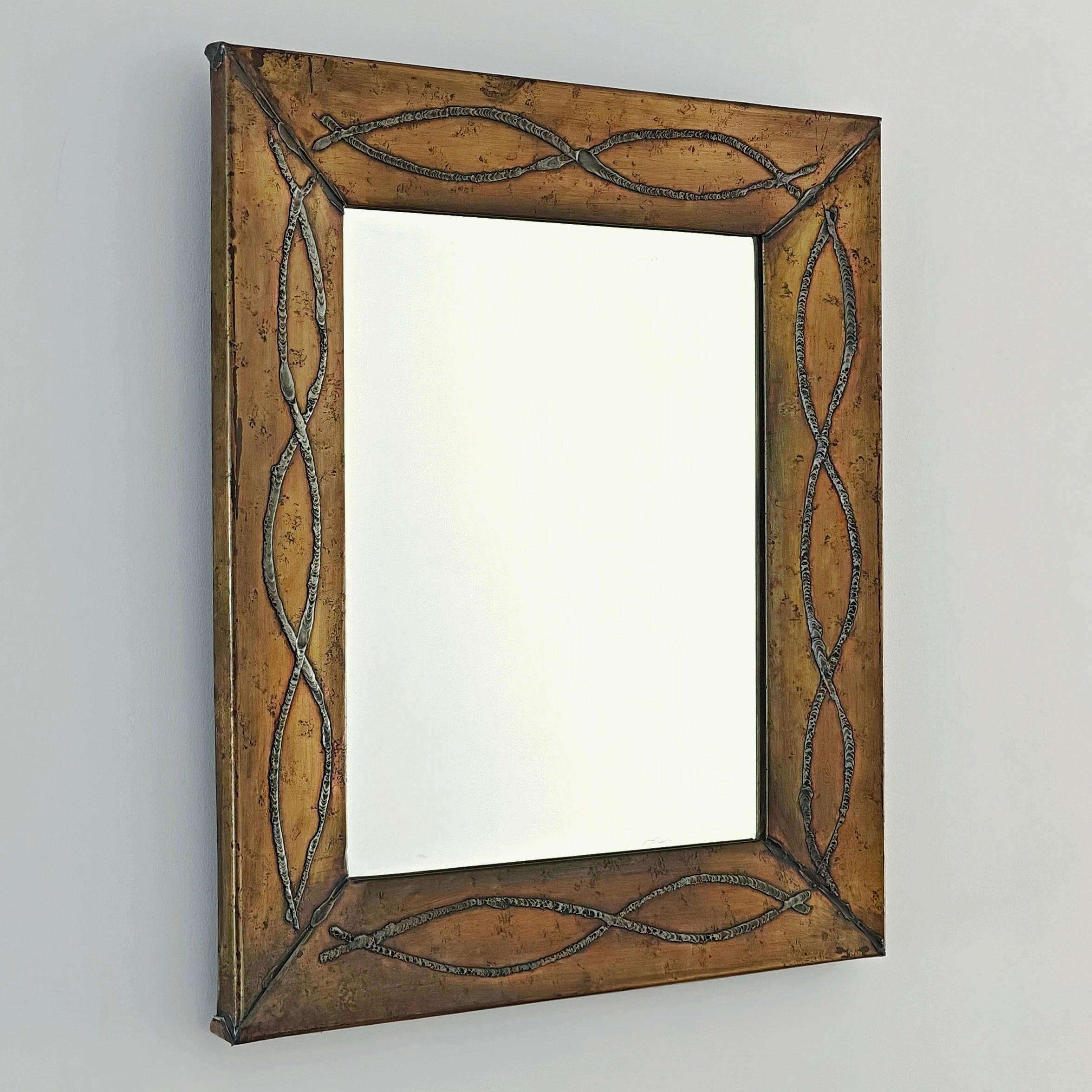 Mirror by the French tin and brass artisan Jean Goardère (20th century), produced in the town of Orthez in the Pyrénées Atlantiques region. This mirror features an abstract decoration that can be interpreted as fish. The frame’s decoration is made