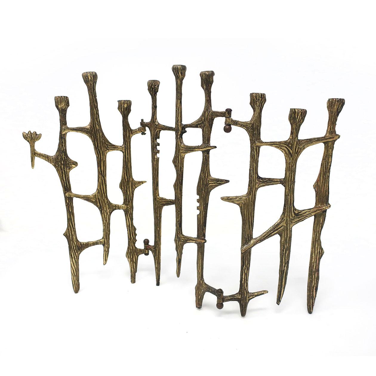 A vintage Brutalist brass candleholder that could be used as a menorah or hanukkiah. With a rich patina and thornlike sculpting, this unqiue piece folds flat and shows light wear consistent with age and use. Unsigned but very likely by Wainberg of