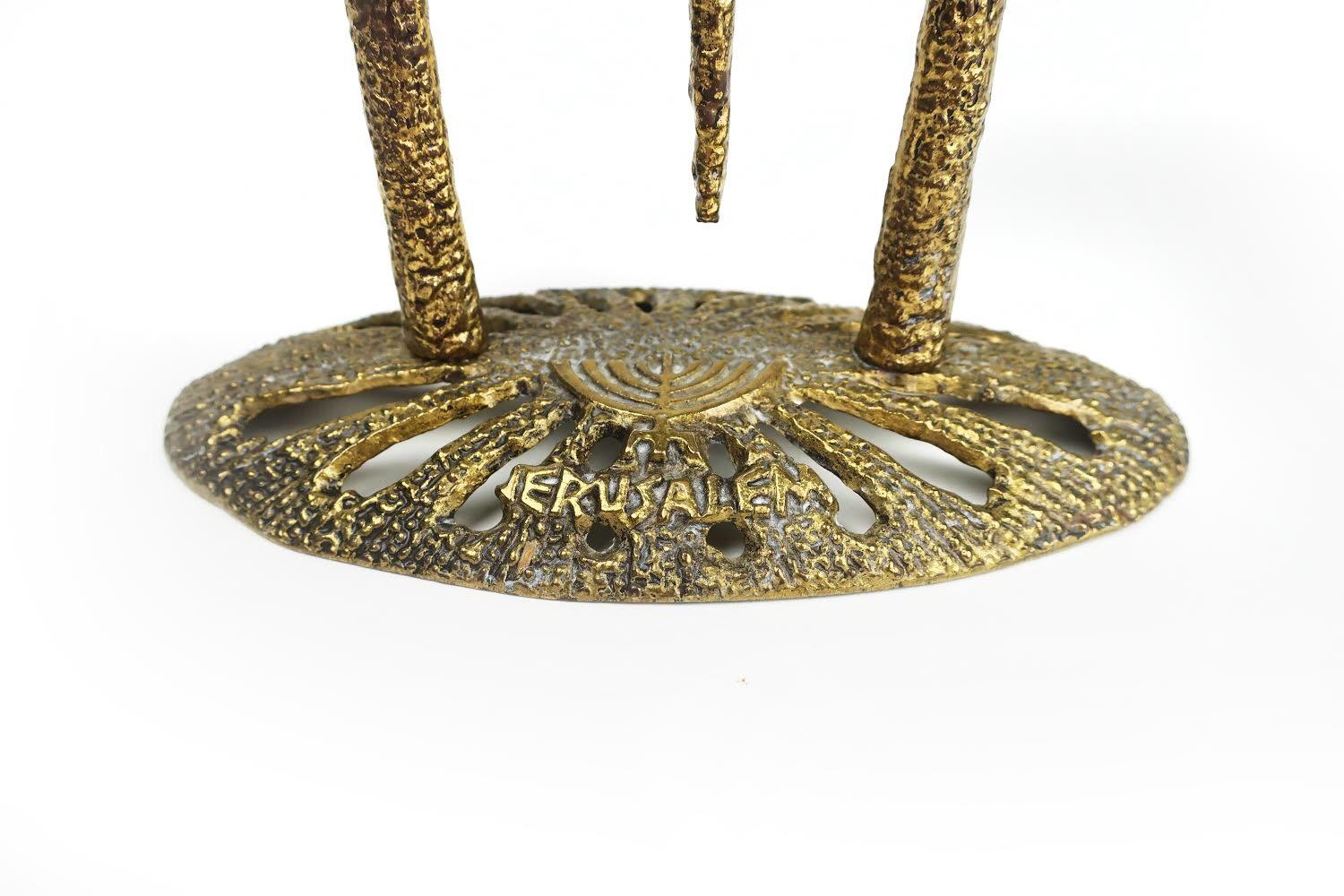 A vintage brass Wainberg Brutalist menorah with an oval base that says 'Chanukah' and 'Jerusalem' and three adjustable candleholders. Each of the 3 sets of three candleholders pivot individually.

Beautifully cast and in excellent vintage