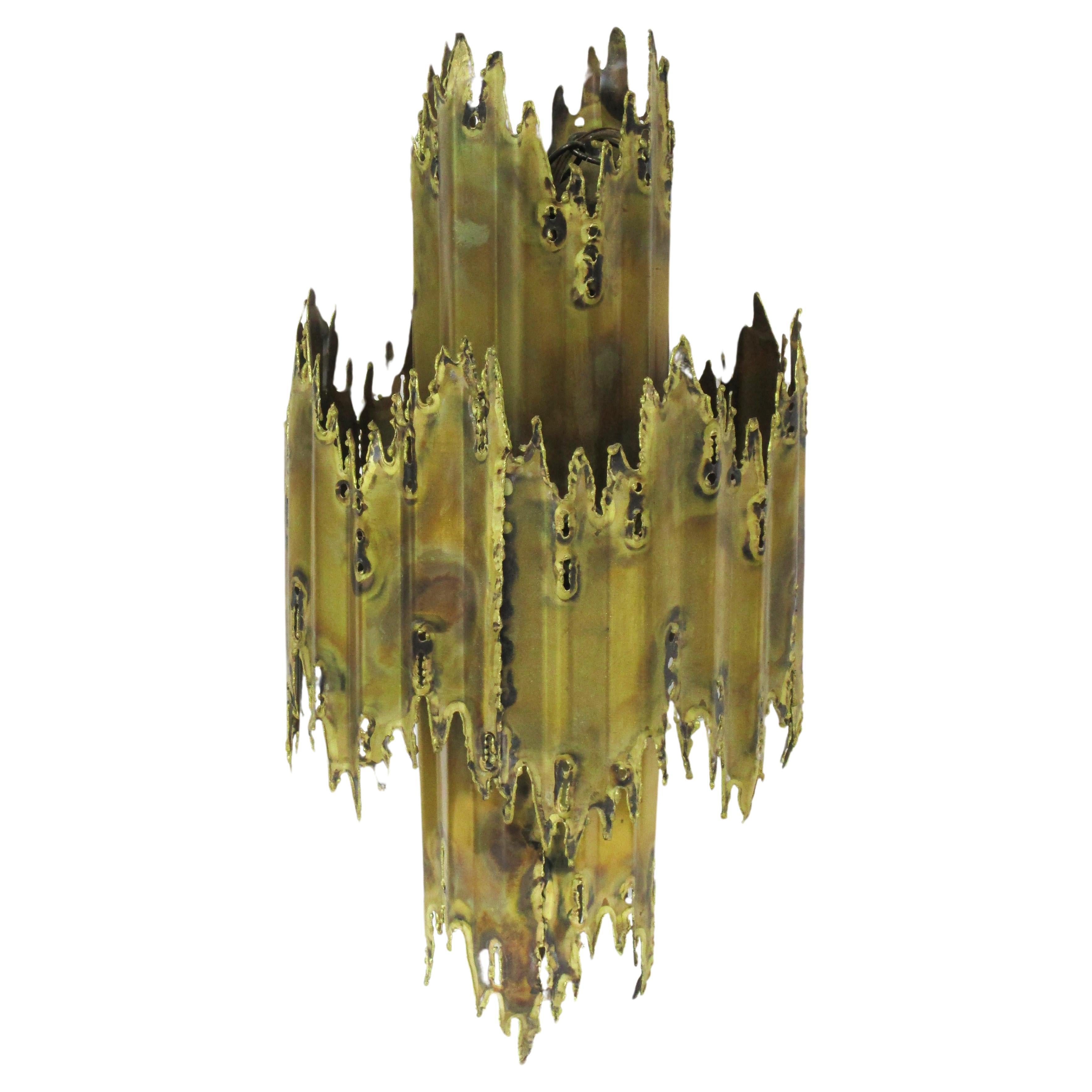 Lustre sculptural Brutalist en laiton découpé au chalumeau et soudé, avec médaillon de plafond encastré assorti, suspendu à une chaîne de 24,5 pouces. Conçue par Tom Greene, connu pour son travail créatif d'éclairage en métal dans les années 60 et