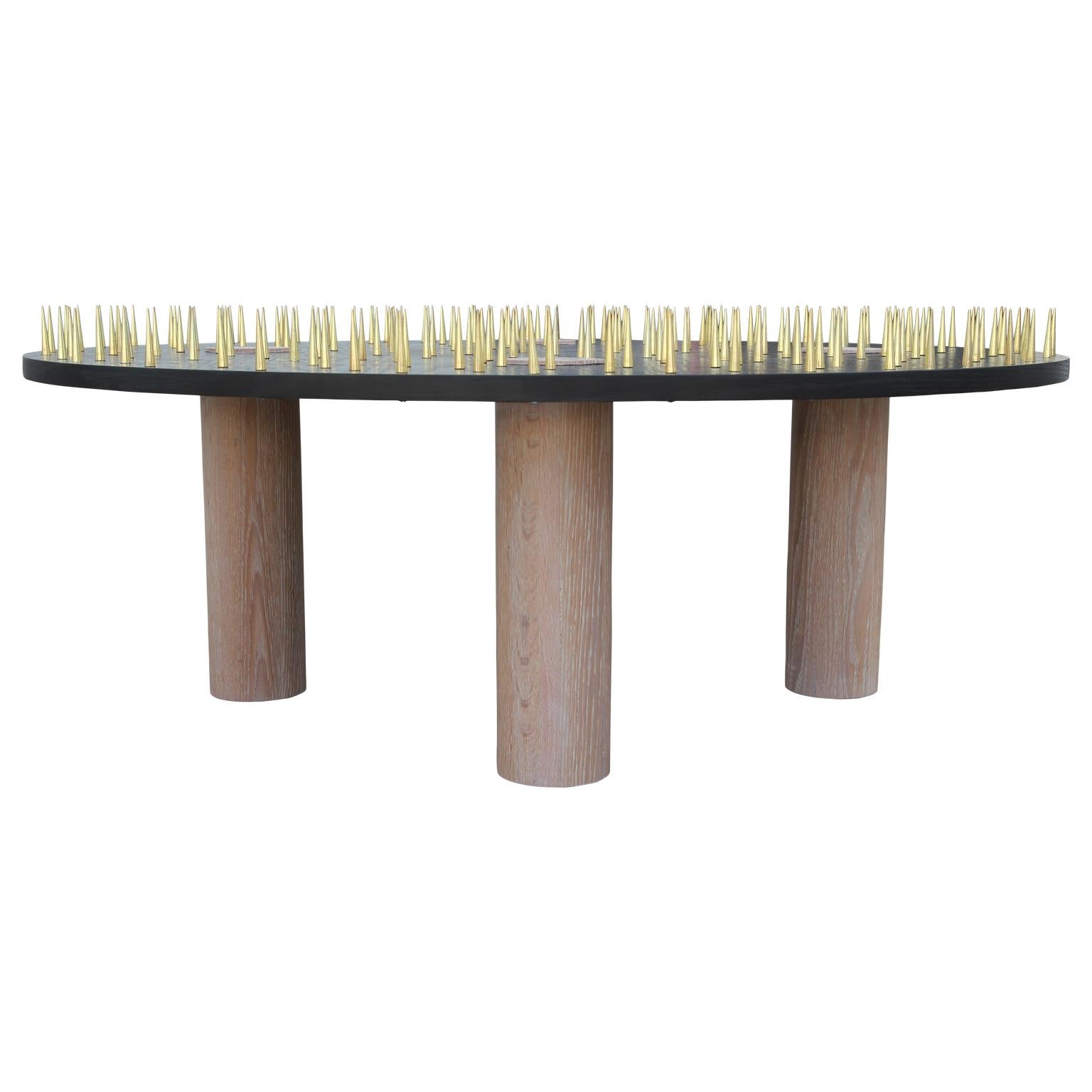 A bold and functional piece of art for your room. This custom round coffee table features over 200 solid brass spikes spread across the top. Solid white washed oak legs protrude through the black stained top which can be used as coasters if desired.