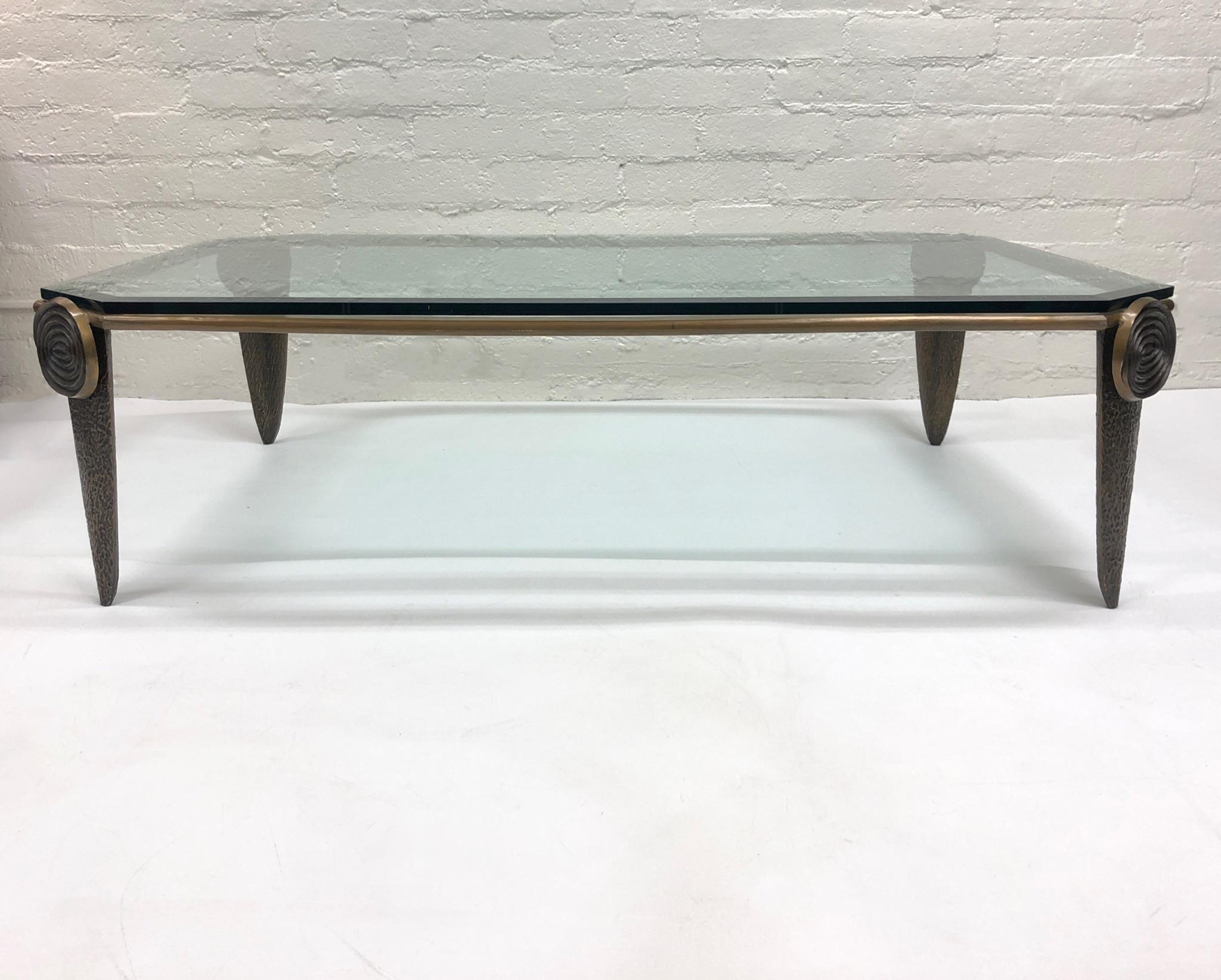 Solid bronze and beveled glass brutalist cocktail table by American Sculptor Tom Corbin. 
Constructed of solid bronze with a 3/4” thick beveled glass top. 
The table show minor wear consistent with age. 
Measurements: 60” wide, 42” deep 16.5”