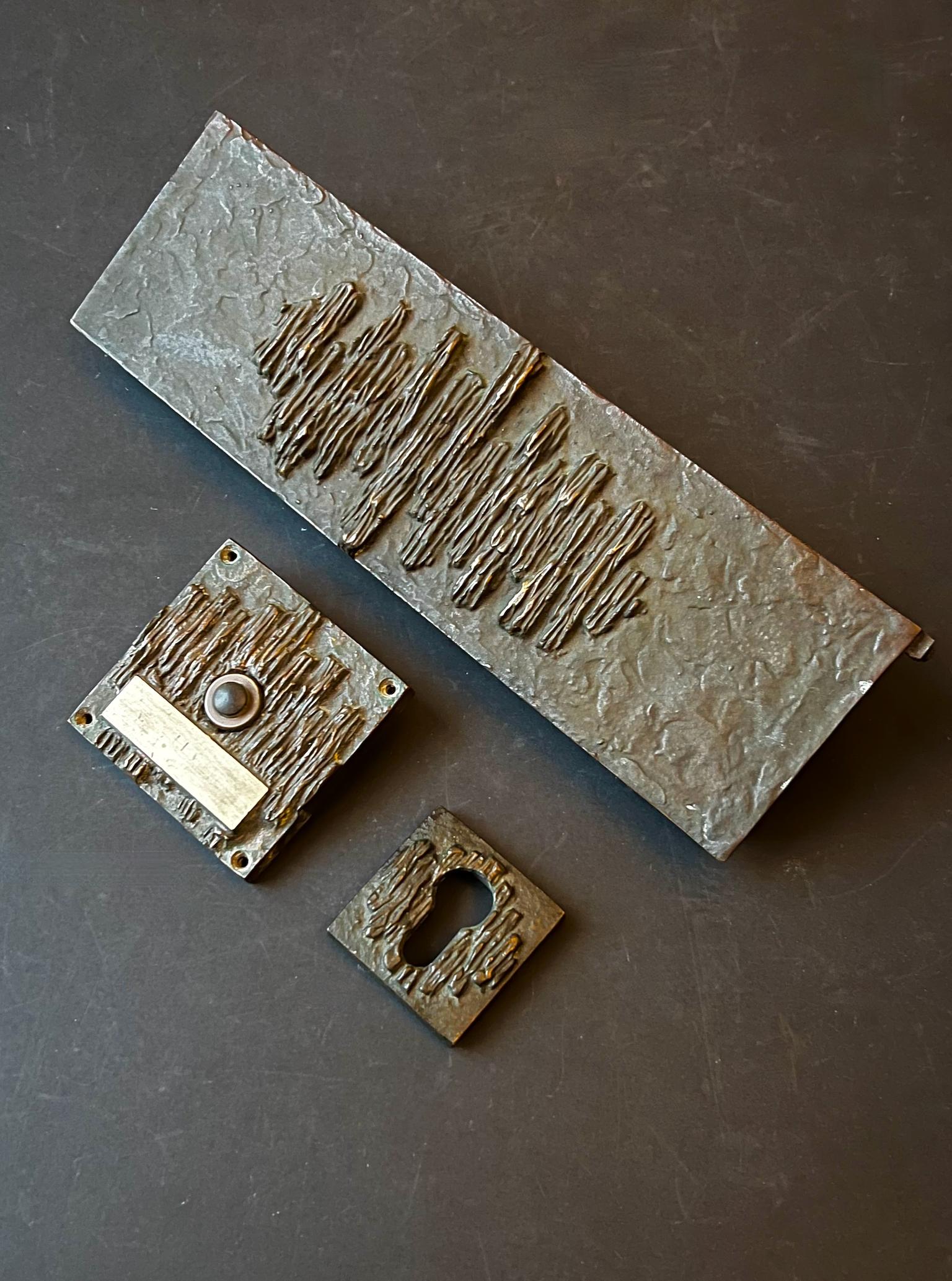 Türbeschlag aus Bronze, bestehend aus Briefkasten, Klingelknopf und Schlüssellochplatte. Zweite Hälfte des 20. Jahrhunderts, gefunden in Deutschland.

Die Stücke sind aus Bronze gegossen, mit den Details eines gemeinsamen abstrakten Musters. Alles