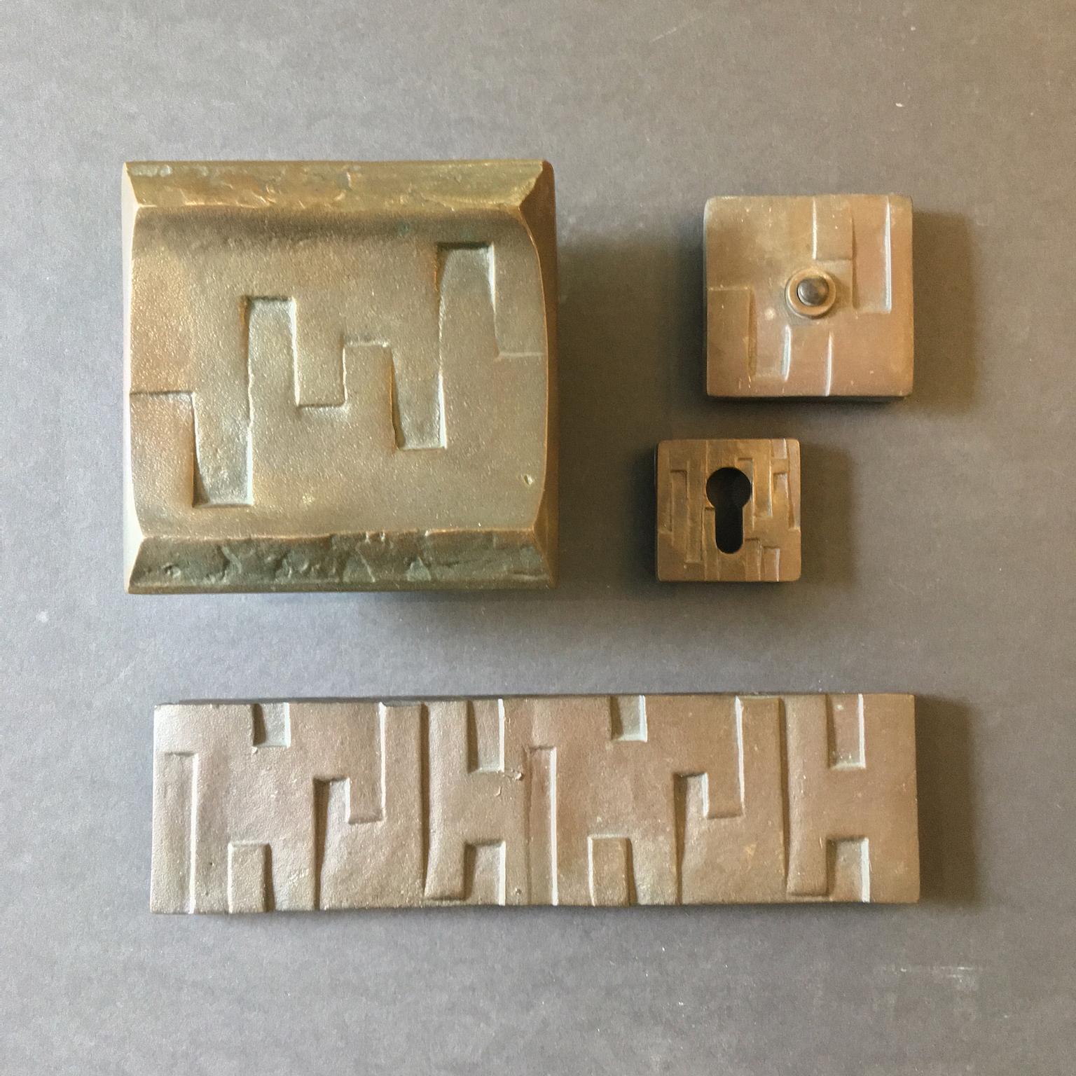 Brutalist bronze door handle and fittings with geometric design. The set includes a matching letterbox cover, bell push (not tested) and escutcheon or keyhole plate, European, mid-20th century.

The items in this set have been left as found,