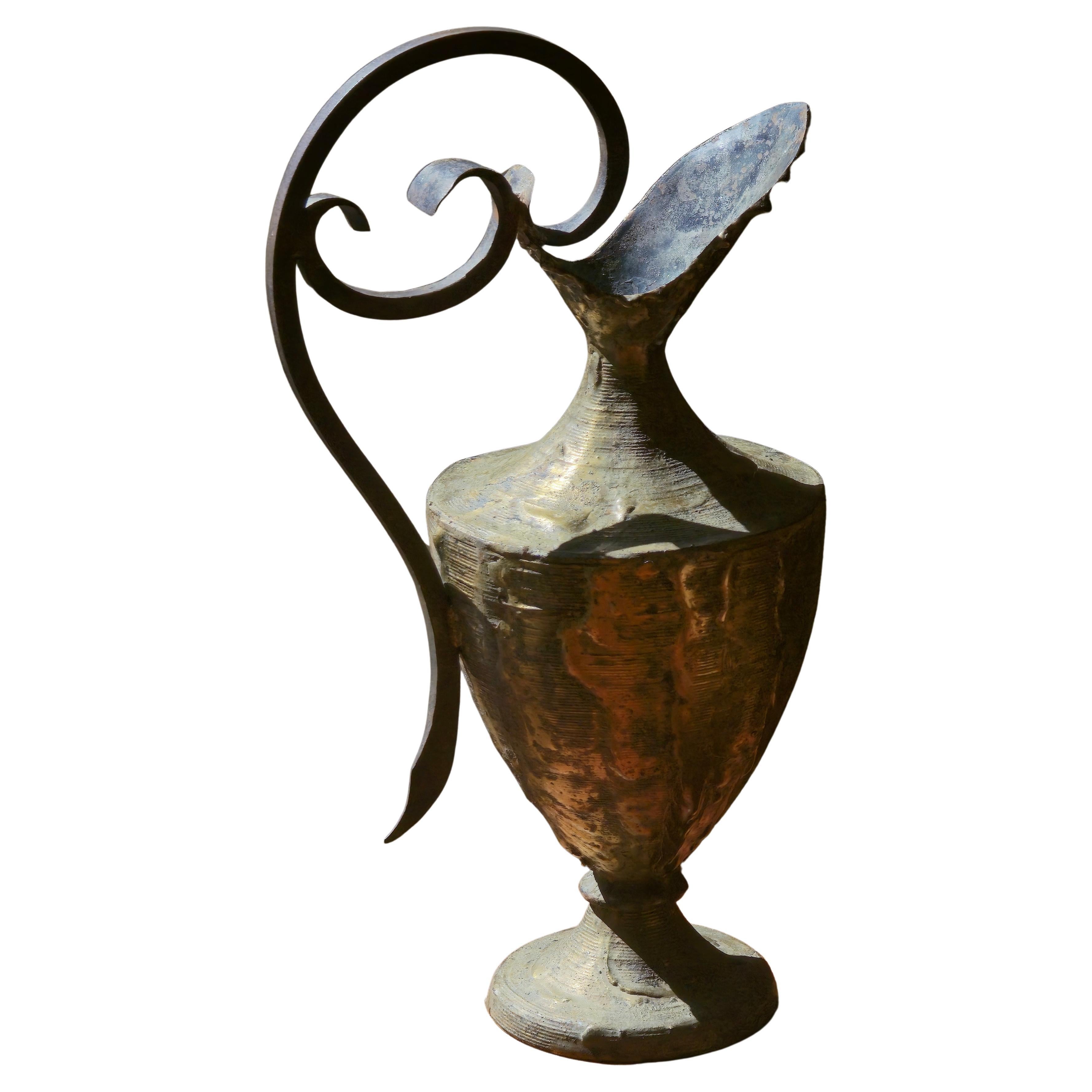 This expressive bronze pitcher was created by French sculptor Max Bré around 1970. Its organic silhouette is enhanced by a raw, textured surface and a bold, sculptural handle that coils upward in a dramatic curve. The asymmetrical spout adds