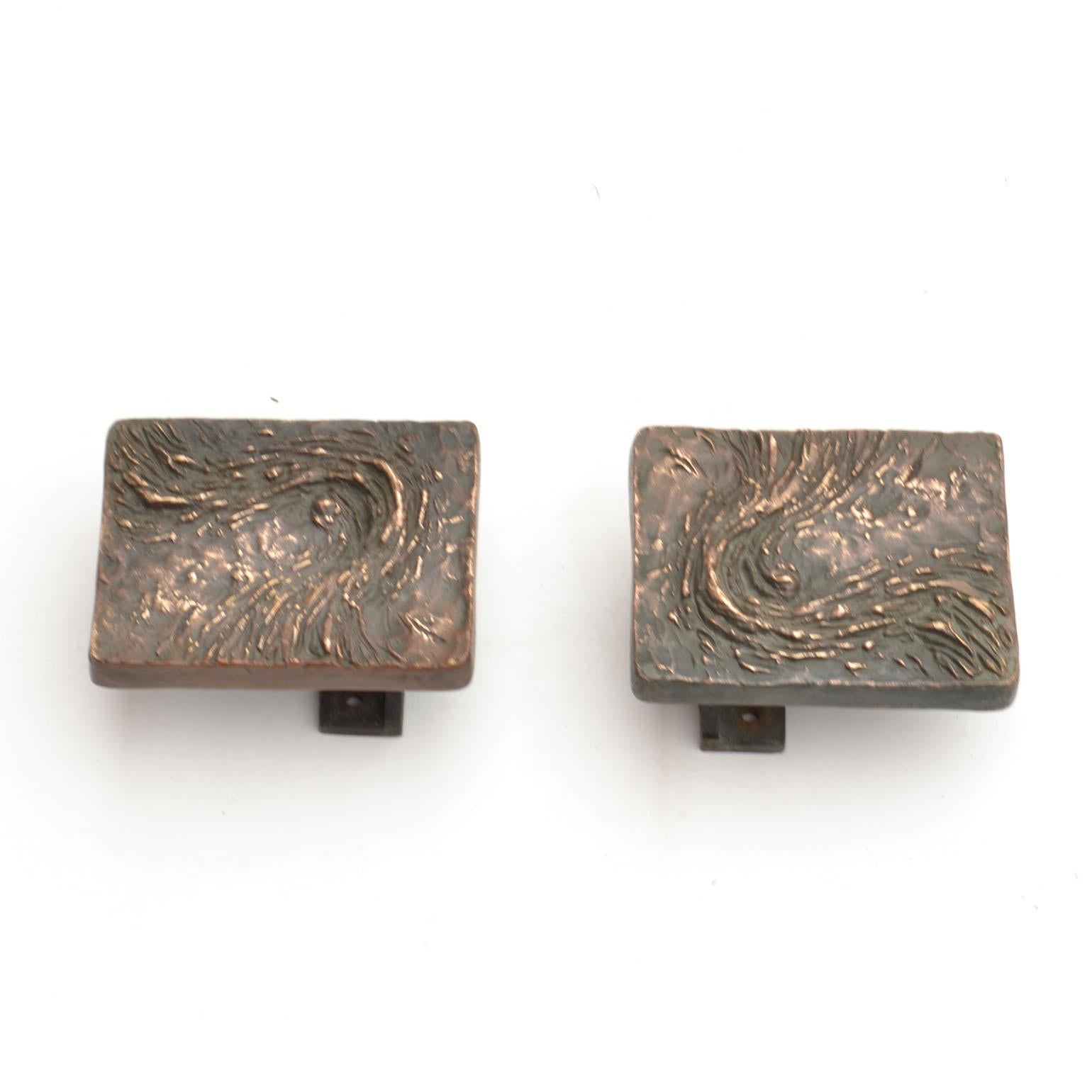 A set of three double push and pull square door handles with abstract relief. They are unused bronze door handles with an abstract textured motif, produced in the 1970's, the bright patina enhances the expressive relief. 
The identical handles can