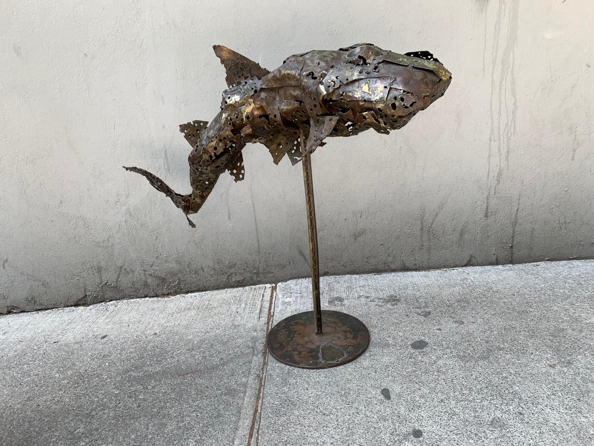 A 1970s Brutalist bronze sculpture depicting a shark. The shark's body is made with welded fretted bronze sheets. The base shows an unidentified monogram 