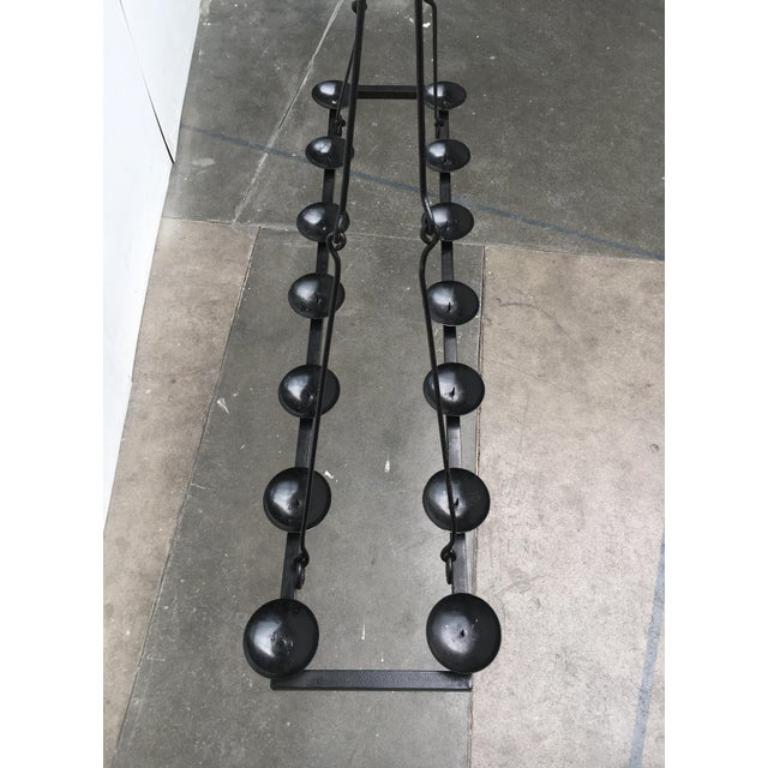 Chandelier brutaliste. Un objet imposant.
Un design fonctionnel avec des éléments en fer forgé. La forme de base est un simple cadre rectangulaire fait de tubes carrés au sommet duquel sont alignés des chandeliers en forme de bol. Le chandelier est