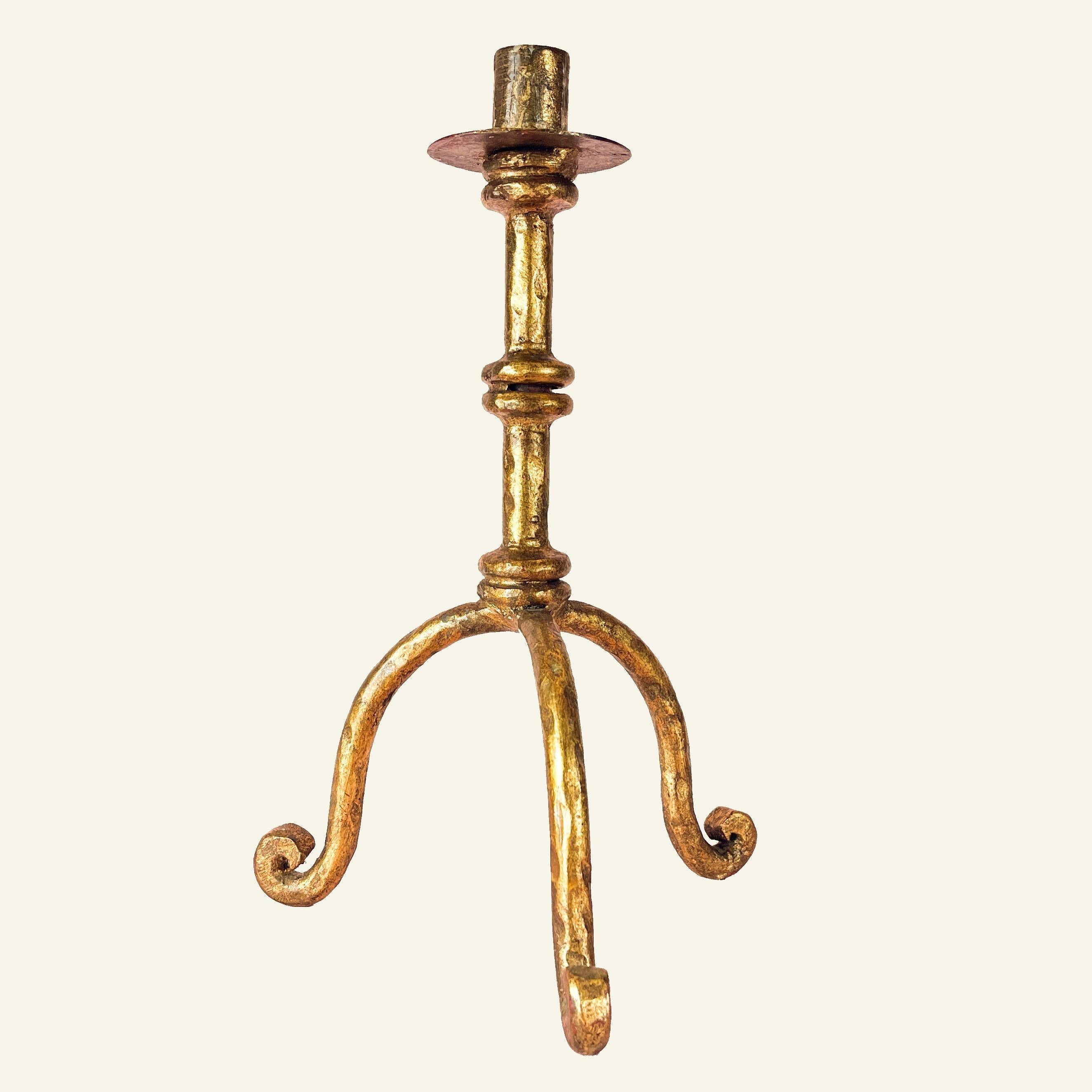 A candle-holder in wrought iron. It is plated with gold leaf and patinated, resting on three curved feet.

This piece is in Brutalist style and was manufactured in the 1950s. It compares to some of the works of Maison Ramsay and Henri