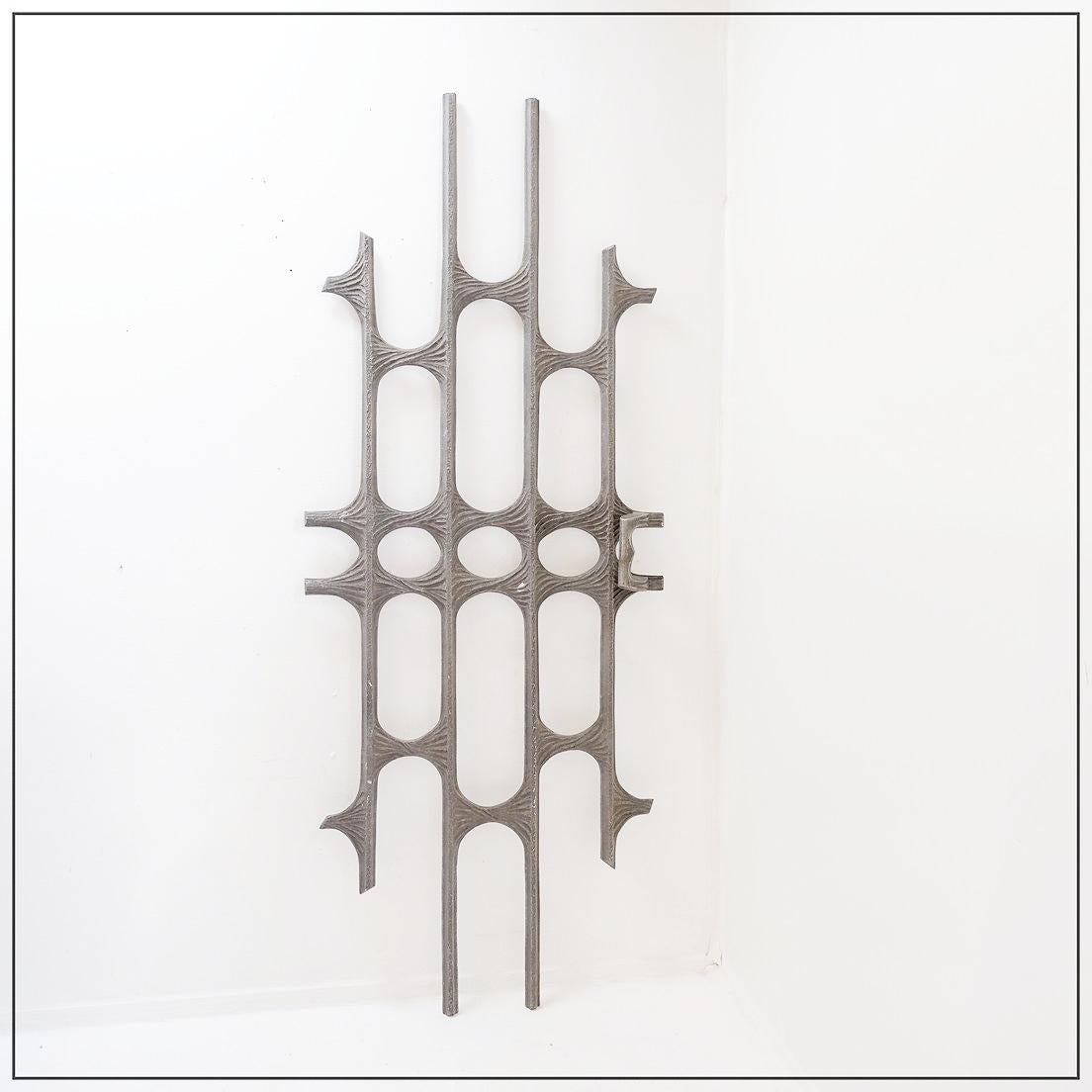 Wall sculpture - abstract decoration
Large cast aluminum door panel from the 1960s. Its brutalist design is clearly influenced by the metal sculptures associated with Paul Evans. The contrast between the rigid linear elements and the fluid central