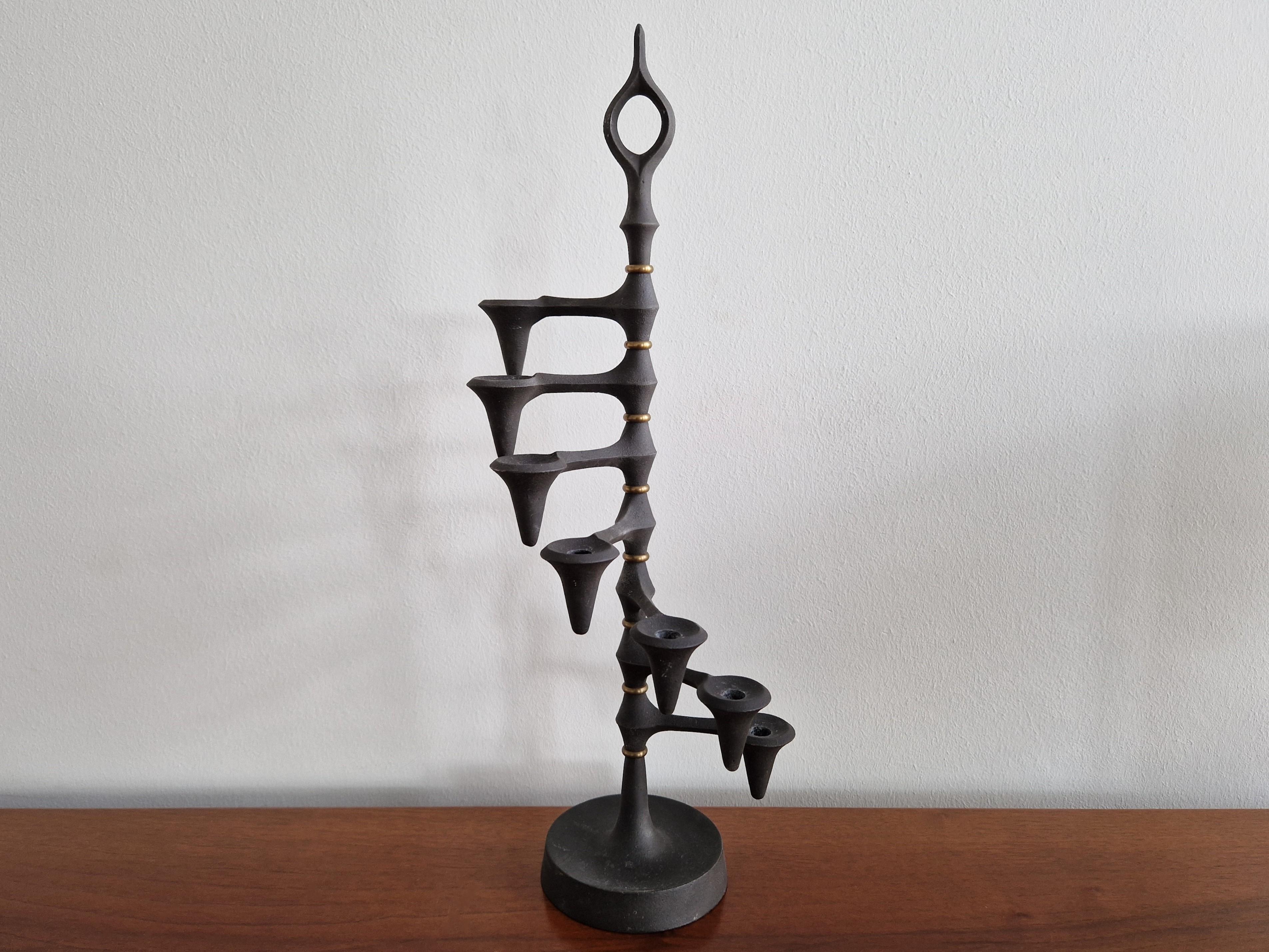 This iconic candelabra or candle holder was designed by Jens Quistgaard in the 1960s. A brutalist design that is made out of cast iron and brass. It has 7 adjustable arms that can rotate in any position. It is in a good condition with some signs of