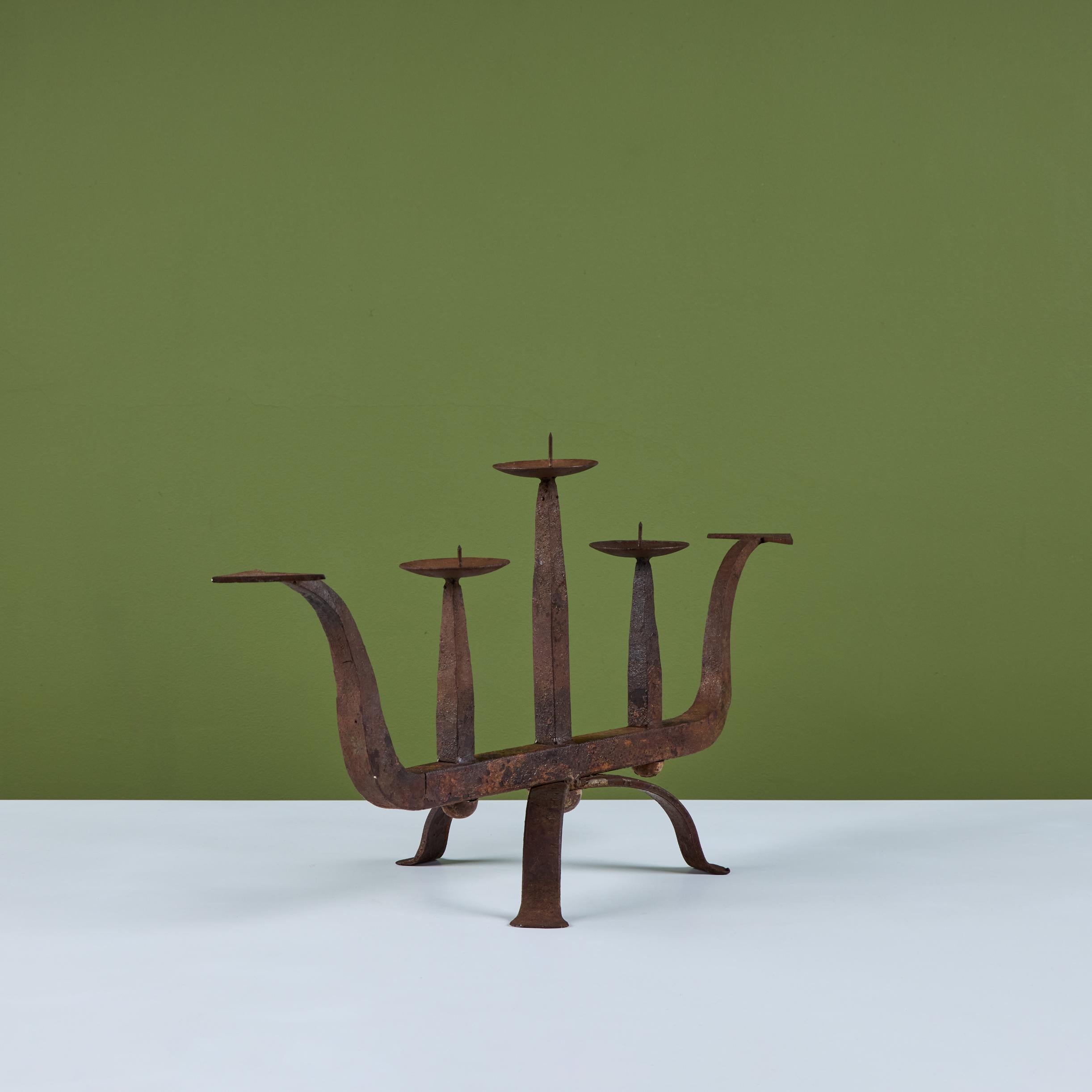 Cast iron candelabra. This example is set on a tripod base with a curved frame that comes to a point on each end. Featuring three round basins with rounded plates and center spikes to hold the candles.

Dimensions
25.5