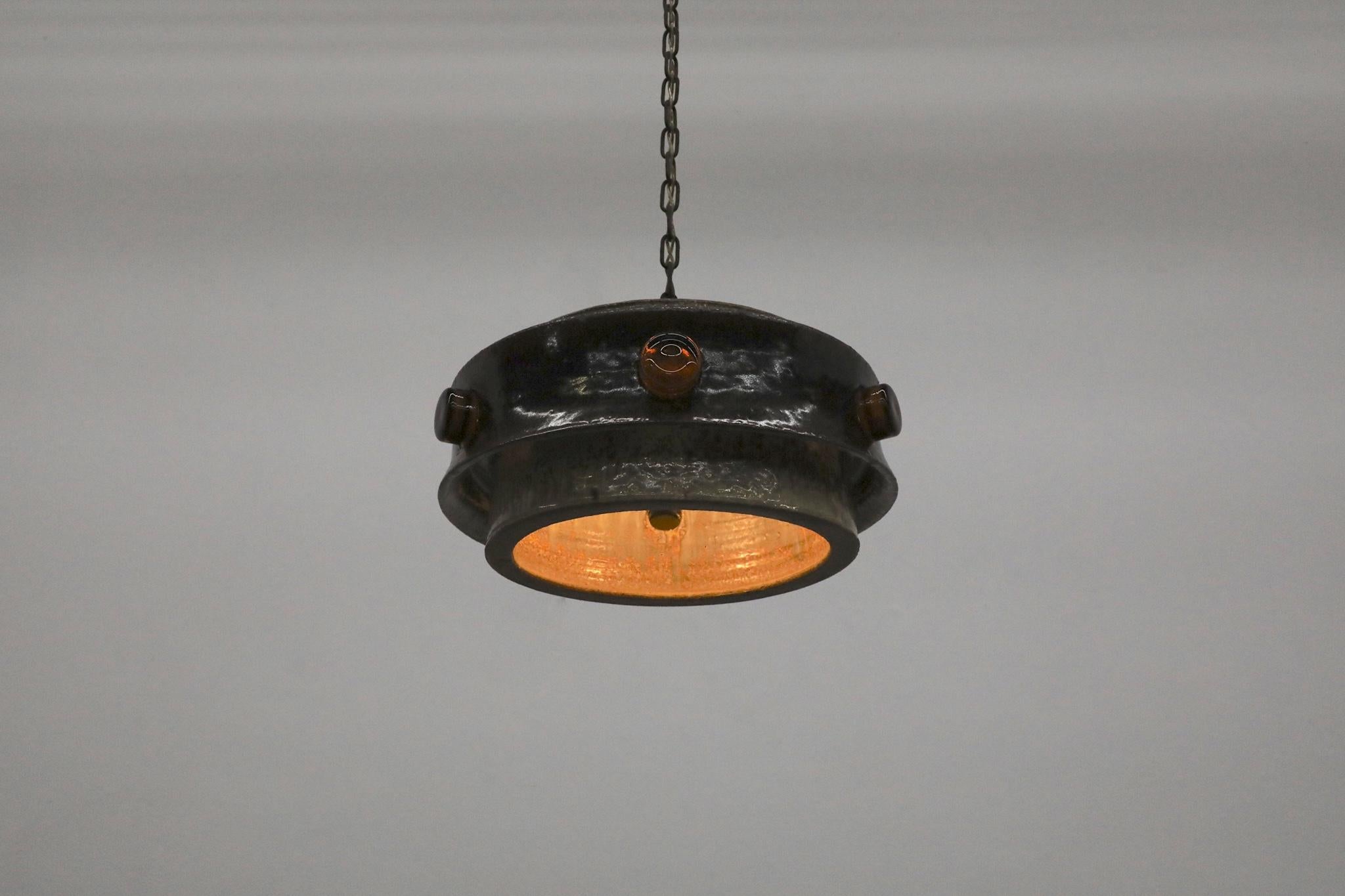 Impressionnante suspension OVNI en céramique lourde avec verre ambré et découpes par Jette Hellerøe pour Axella, Danemark, années 1970. Des tons de brun magnifiquement glacés complètent les touches d'ambre, soulignant ainsi l'élégance de l'ensemble.