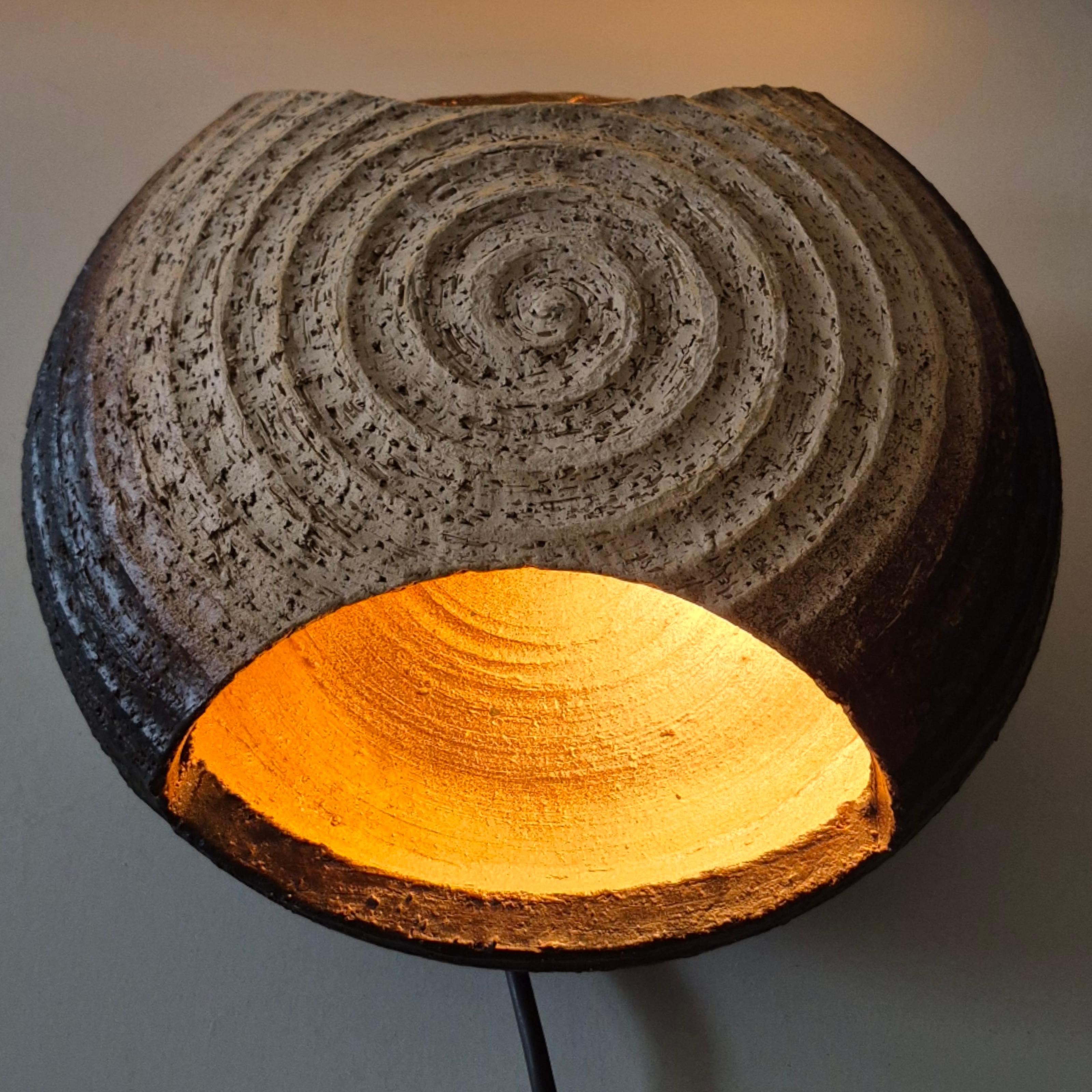 Round ceramic wall lamp. The lamp has two openings for the light to shine through. It is Matt glazed in earth tone colors with a spiral decor in the facade of the lamp.
The lamp is in very good condition and fully functional.
It has no attribution