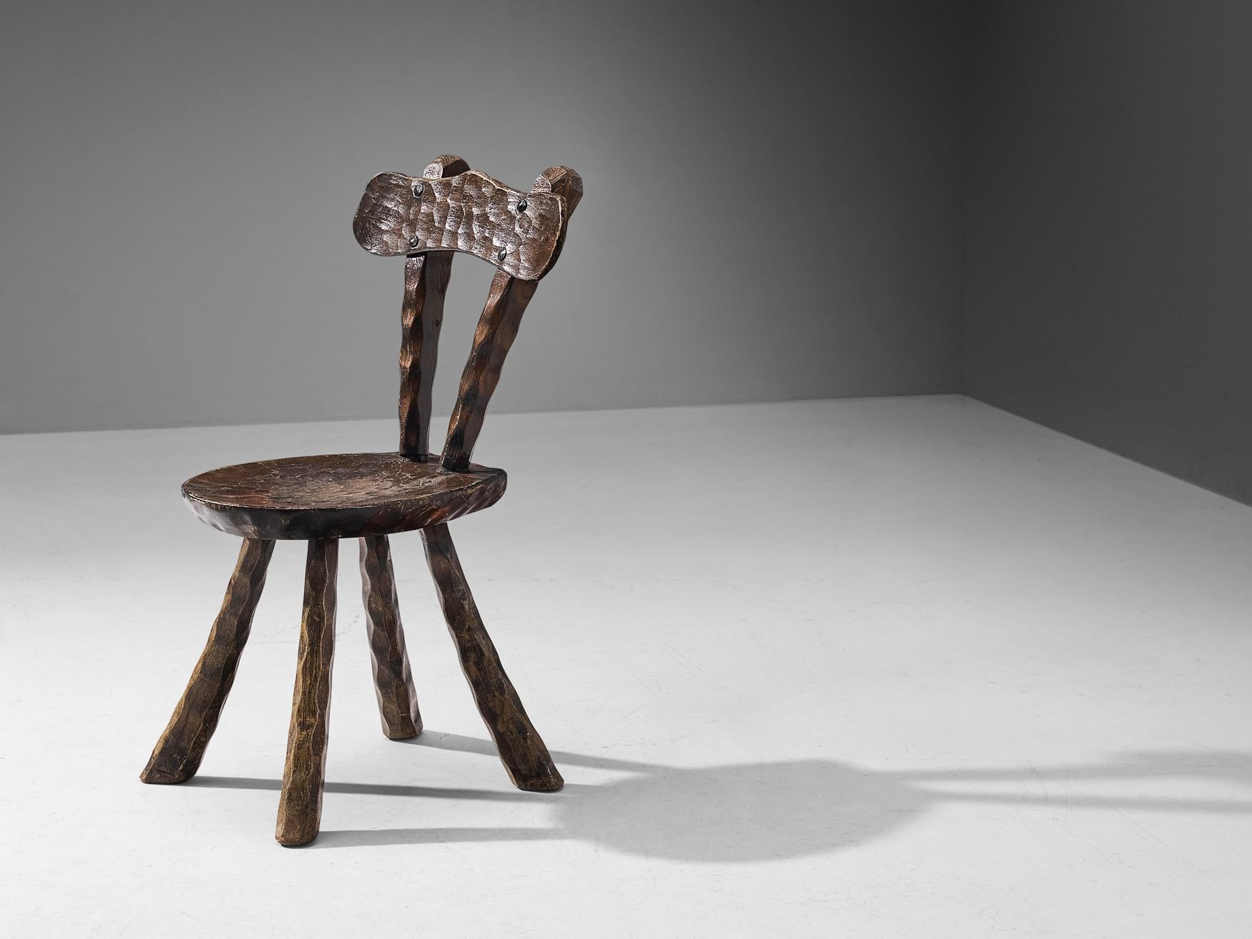 Side chair, dark stained elm, France, 1960s. 

Brutalist chair in the manner of Alexandre Noll. This French chair shows the characteristic traits of his furniture designs; the frame exhibits prominent carving details creating a comprehensive