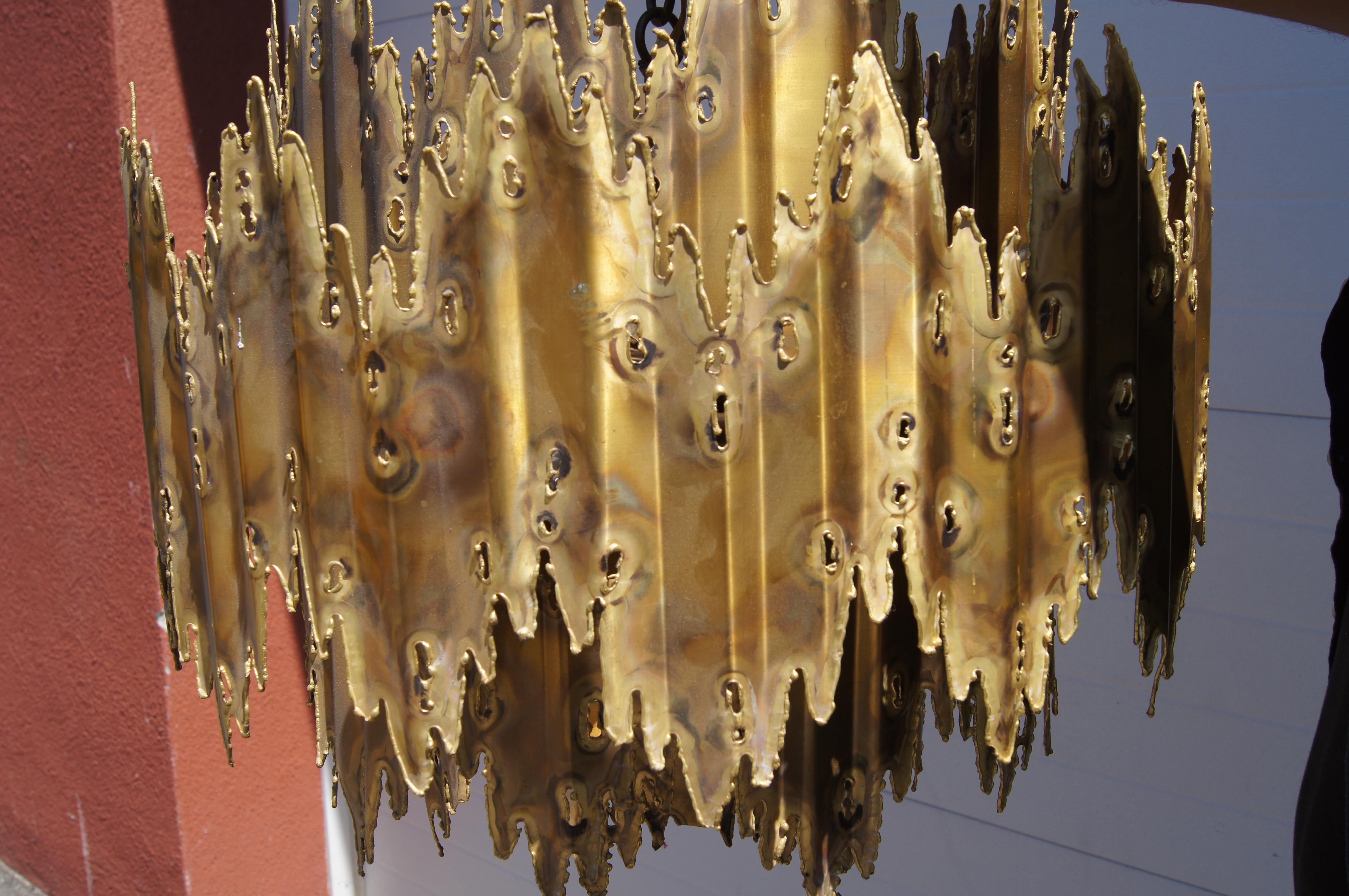 Los Angeles–based metal sculptor and designer Tom Greene created this fabulous brutalist chandelier for the Feldman Lighting Company in the late 1960s-early 1970s. The pendant comprises five staggered tiers of bronze cut free form with a torch, with