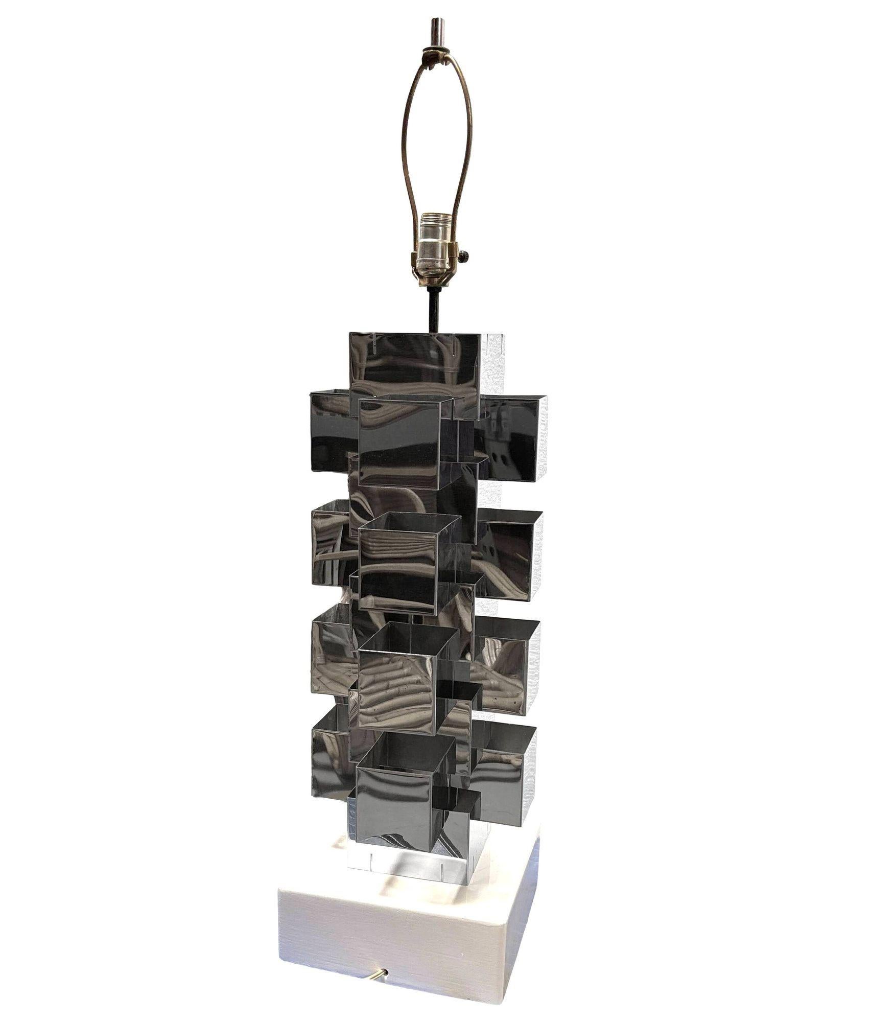 Polished chrome structural table lamp with a square central column composed of interlocking bands resting on a black lacquered base. Chromium-plated steel construction is reduced to basic geometric shapes, with a square base made of black lacquered