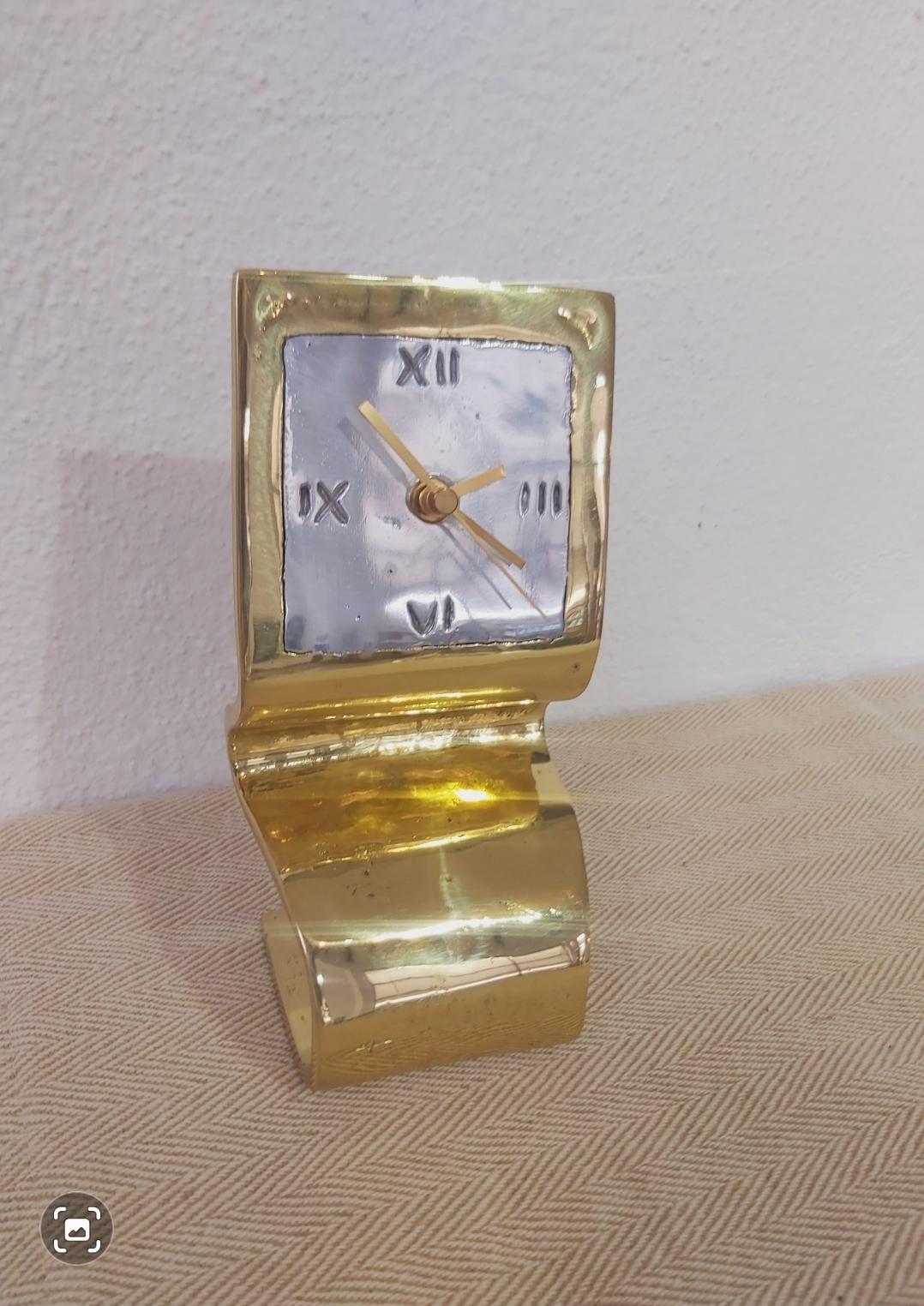 The clock was created by David Marshall, from sand cast aluminium and brass.
 We use recycled materials all our pieces are handmade, mounted and finished in our foundry and workshop in Spain.
It is certified authentic by the Artist David
