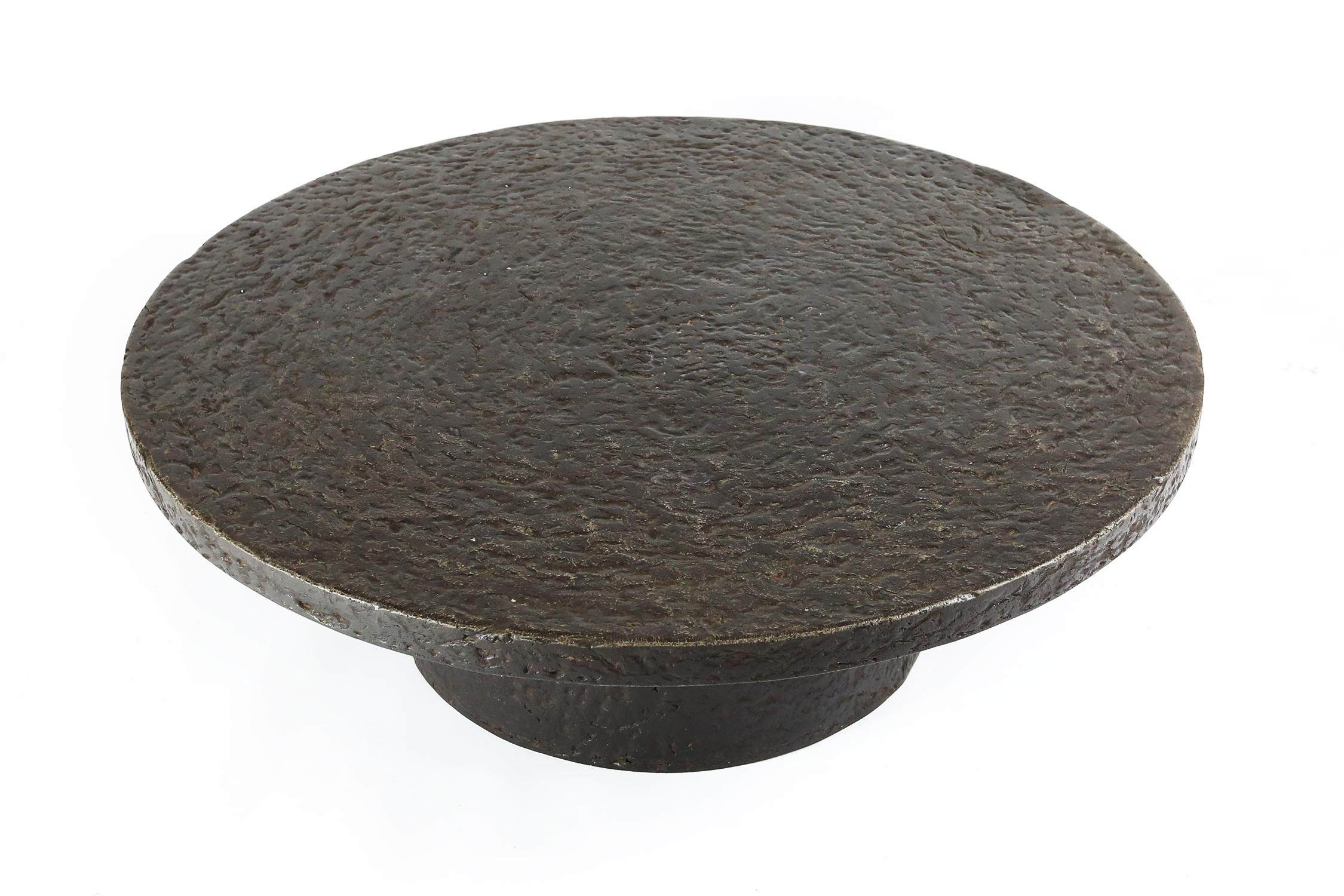 This robust coffee or cocktail table is from the 1970s and probably made in Belgium. The thick round top is supported by a similar but smaller round column. This low table is made out of resin which resembles the appearance of stone. The