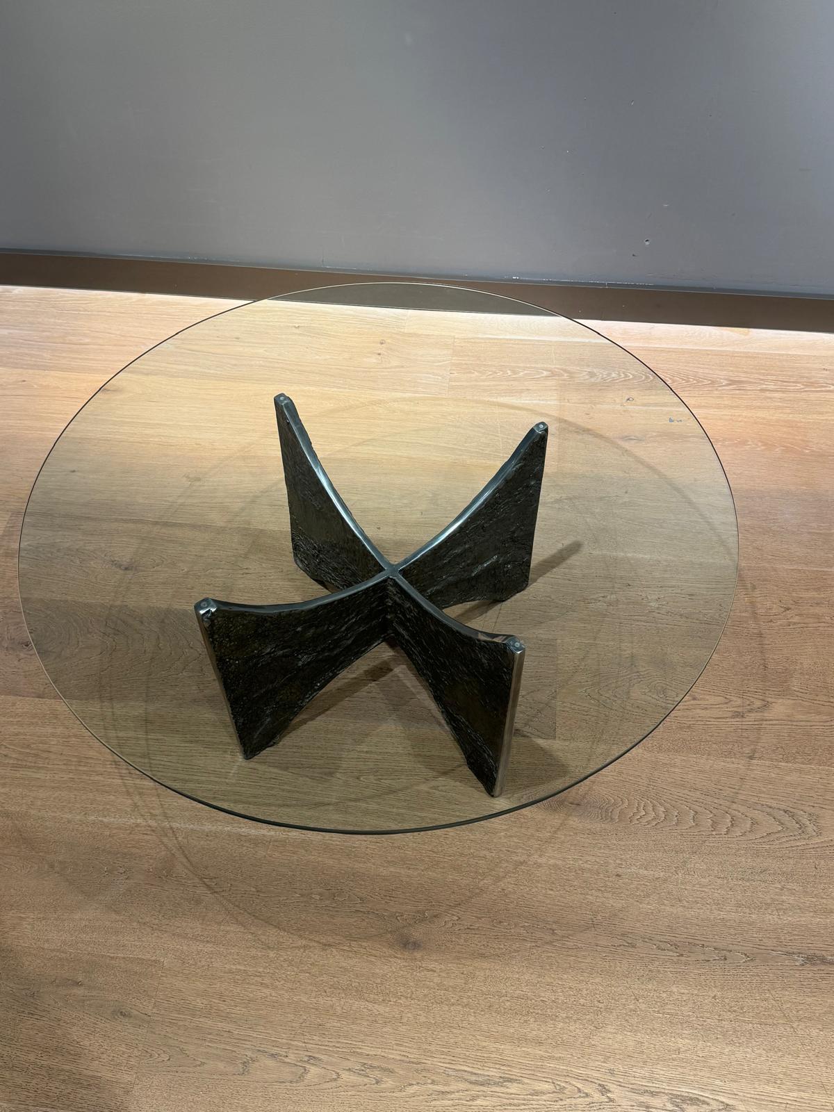 Table basse brutaliste en fonte d'aluminium circa 1965 . La base de la table est en aluminium avec une texture rugueuse. La partie supérieure est en verre trempé.  La forme en croix et la structure de la base sont ainsi révélées sous tous les