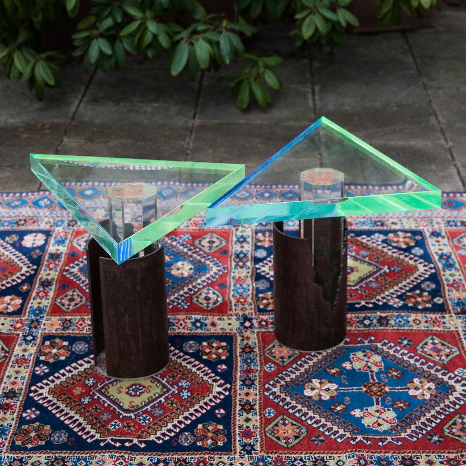Spectacular pair of Brutalist side tables made in acrylic and bronze.
The hexagonal clear acrylic base is framed with a round brutalist bronze and the three cornered top is colored in blue and green acrylic.
A real artist statement of the
