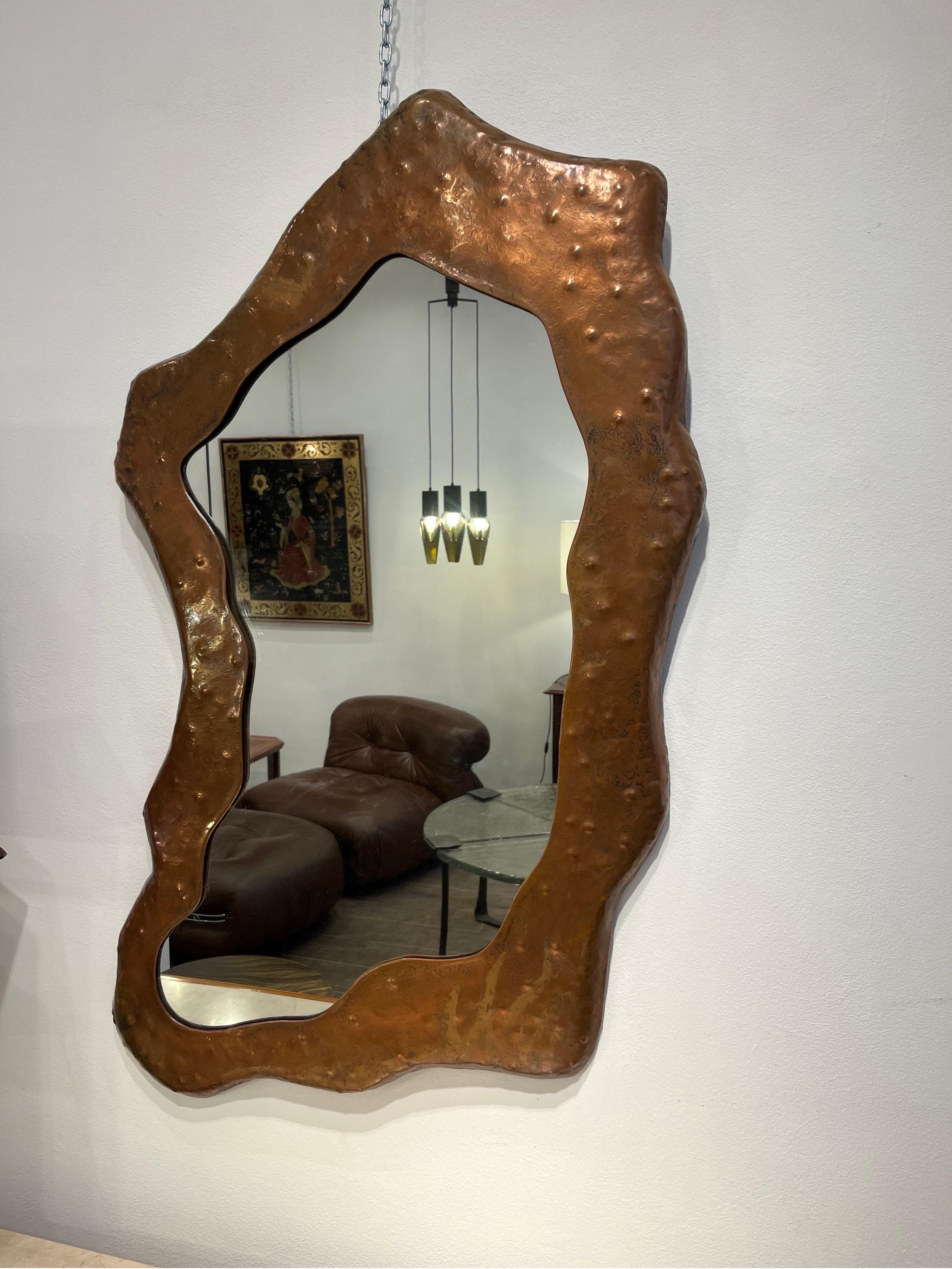 Angelo Bragalini is an Italian designer active in the 1960s-1970s. He mostly designed mirrors in copper. This particular mirror is interesting for its asymmetrical shape. The metal is repoussé to achieve the form and hammered to give some relief and