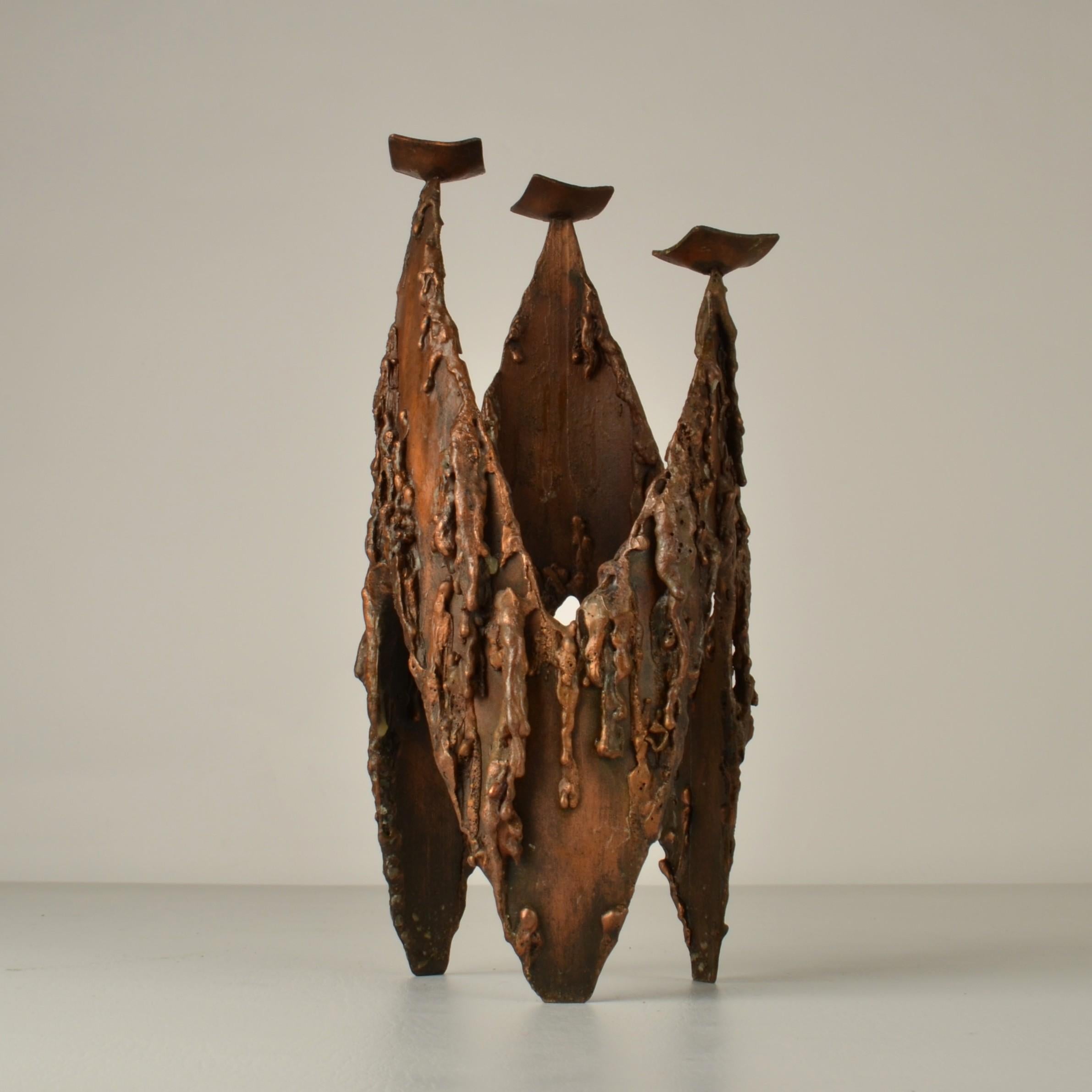 Brutalist three arm copper candelabra made in the 1970's is sculptural and looks like a group of cloaked  figures.. The texture like dripping candles. It has three arms is suitable for regular candles. 