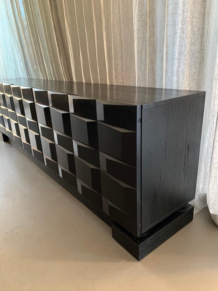 French vintage sideboard in black stained oak veneer with 5 doors, with shelves and drawers for cutlery, napkins, table cloths etc. The sideboard is in the renowned Brutalist style (1950-1980) with its detailed and facetted yet raw and simplistic
