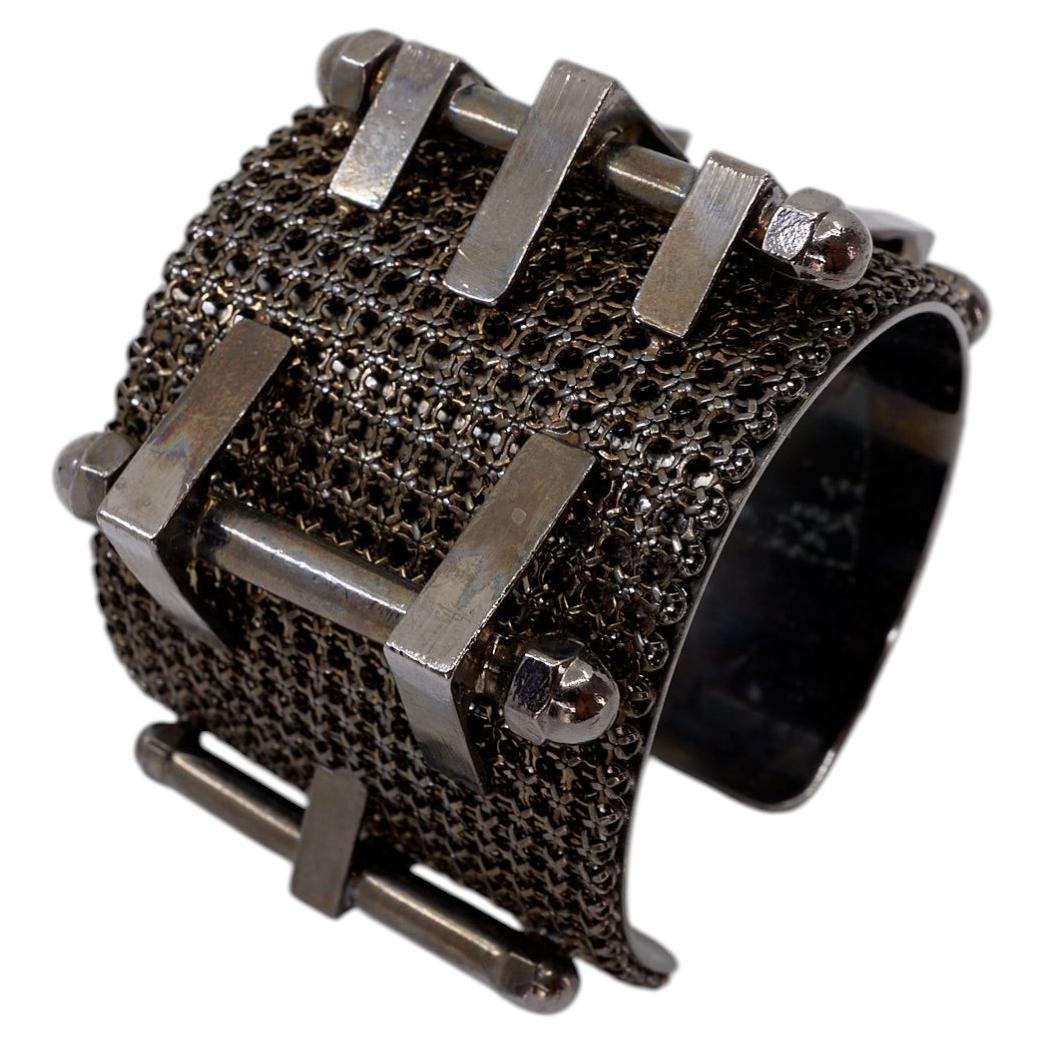 Pieza vintage de estilo brutalista industrial: pulsera tipo esclava con cadena y tachuelas, en rutenio
