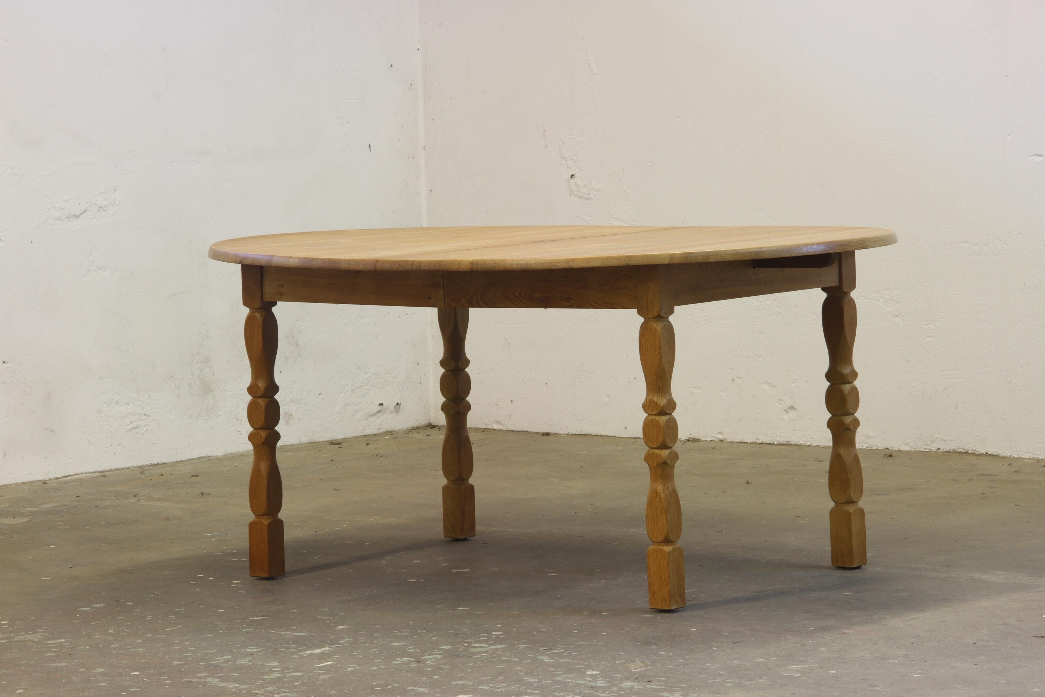 his vintage oak table embodies the spirit of Henning Kjaernulf's celebrated furniture design. Its brutalist aesthetic, marked by intricate leg carvings, is beautifully complemented by a rounded tabletop that softens its bold presence. In excellent