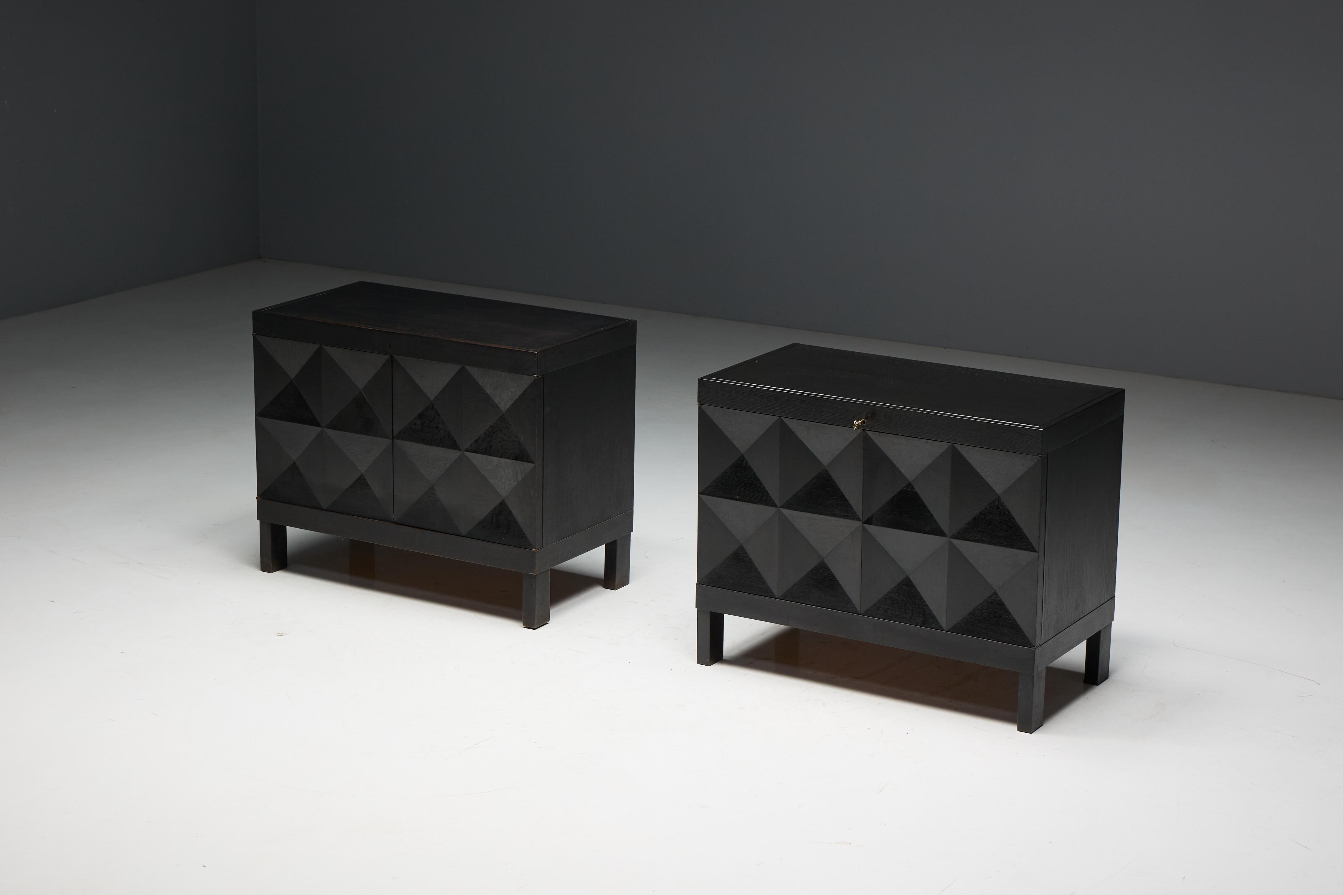 Ces armoires brutalistes de De Coene ont été fabriquées en Belgique dans les années 1970. Fabriqué en chêne teinté noir, il comporte deux portes géométriques à motif de diamant révélant un intérieur spacieux avec une étagère et deux tiroirs. Ses