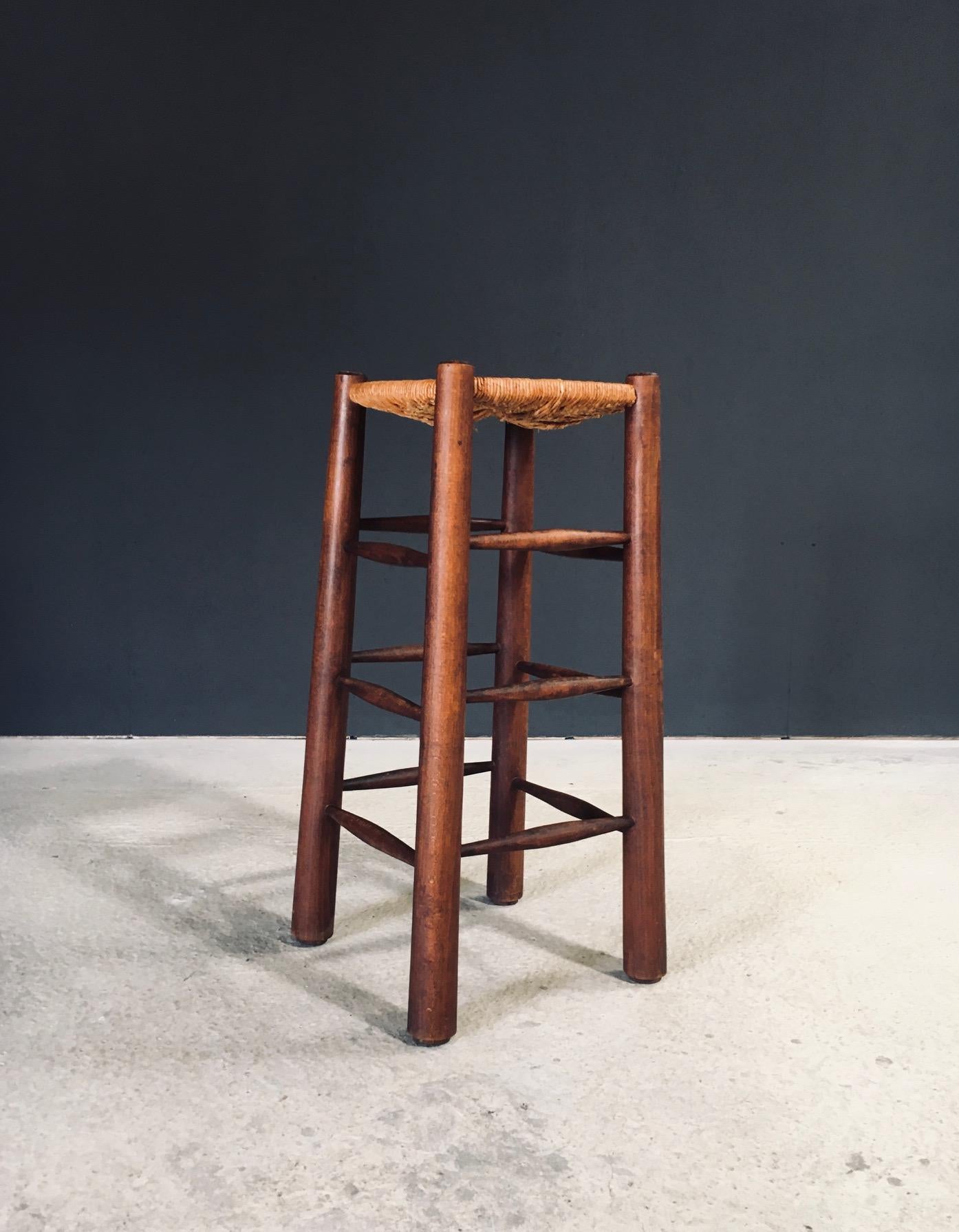 Vintage Brutalist Design Barhocker von Charles Dudouyt. Hergestellt in Frankreich, 1940er Jahre. Massiver Eichenholzrahmen mit spitz zulaufenden Beinen und drei Spindeln auf jeder Seite und einem Sitz aus französischem Binsengeflecht auf diesem