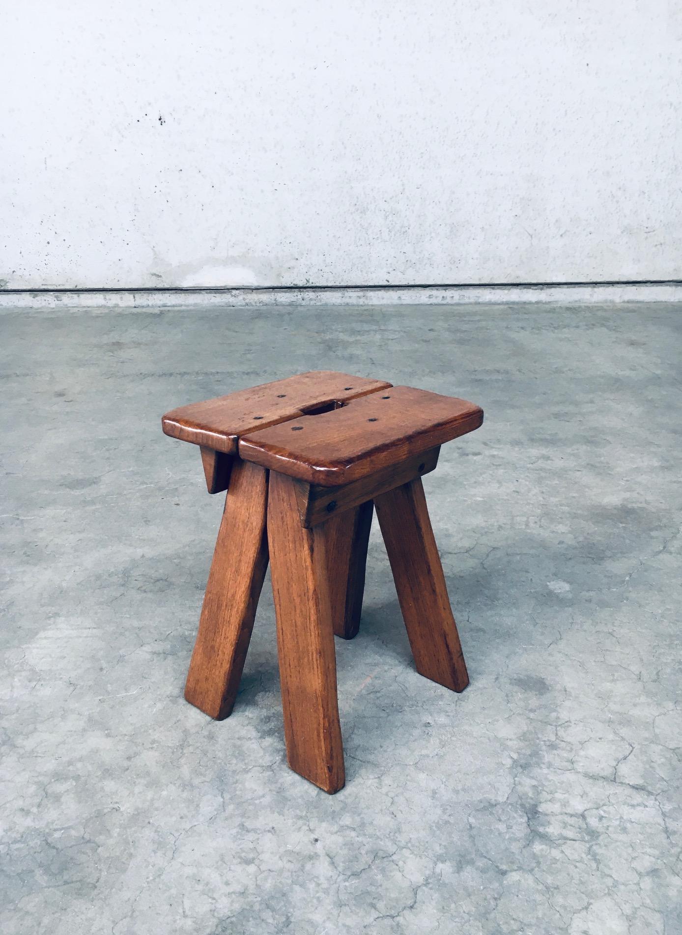 Sgabello con maniglia dal design brutalista vintage. Realizzato in Belgio, periodo anni '60. Sgabello in legno massiccio con apertura a mano per facilitare il sollevamento. I pannelli laterali sono rifiniti con borchie in acciaio. È in ottime