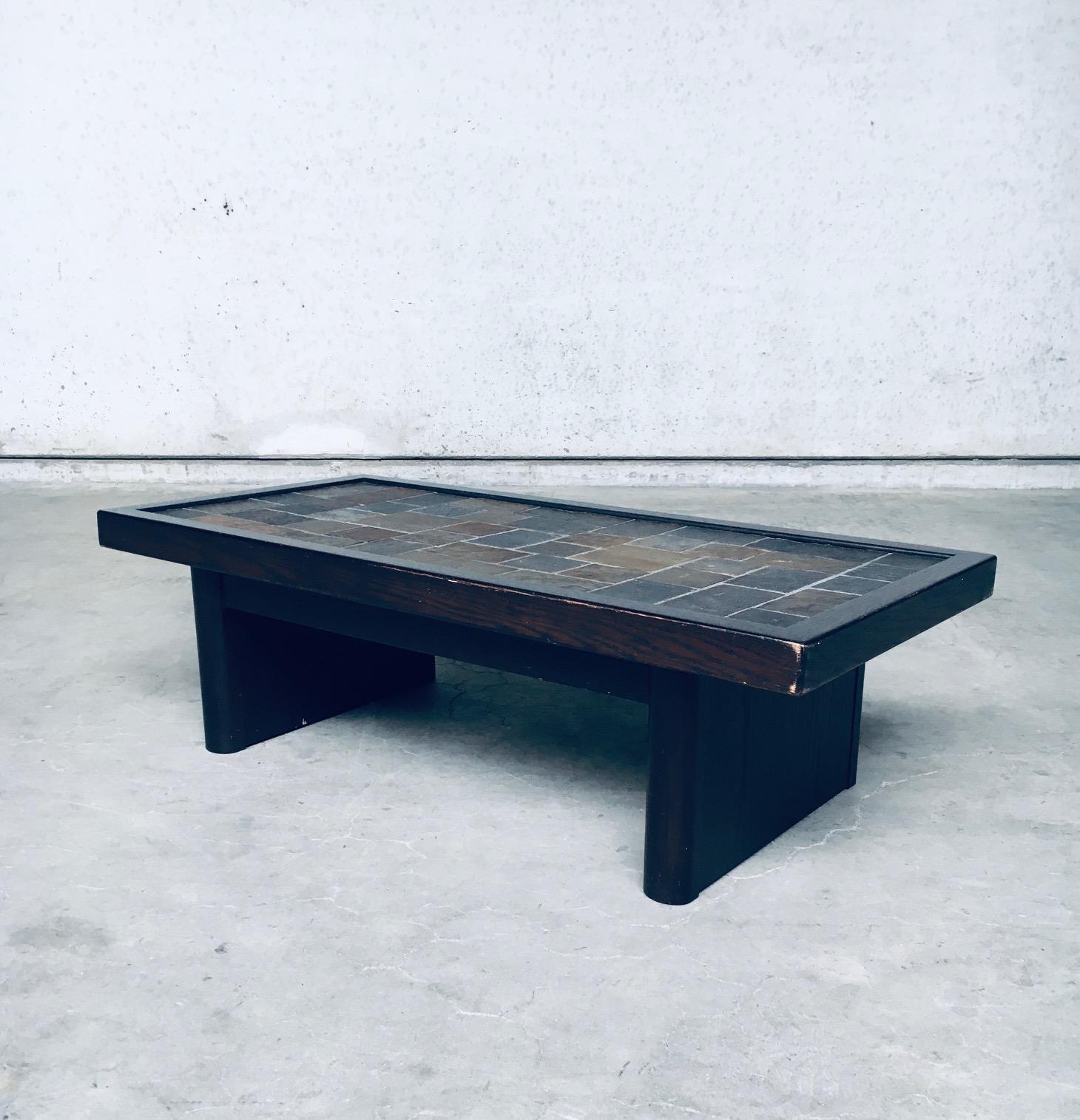 Vintage Brutalist Design Style Slate Tile inlay Coffee Table, made in Belgium 1970's. Dark stained oak wooden frame, and dark stained beech base. Mix of slate tiles in different colors. This comes in very good, all original condition. Measures 128cm