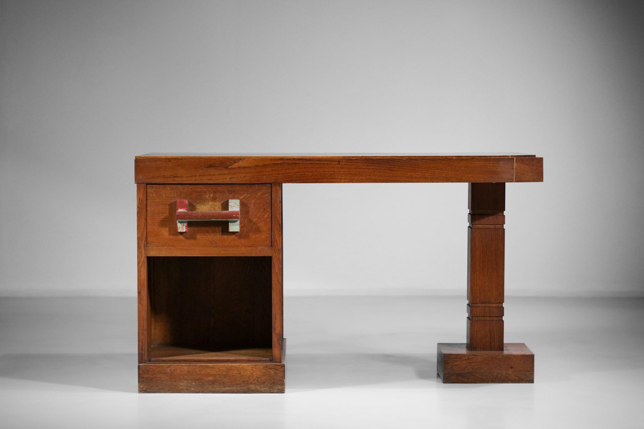 Very nice desk in the brutalist style of the 50s. Solid oak structure and veneer on the top. Composed of a drawer and a shelf on the front side and two shelves on the back side. Detail to note of the painted handle kept on purpose for its nice