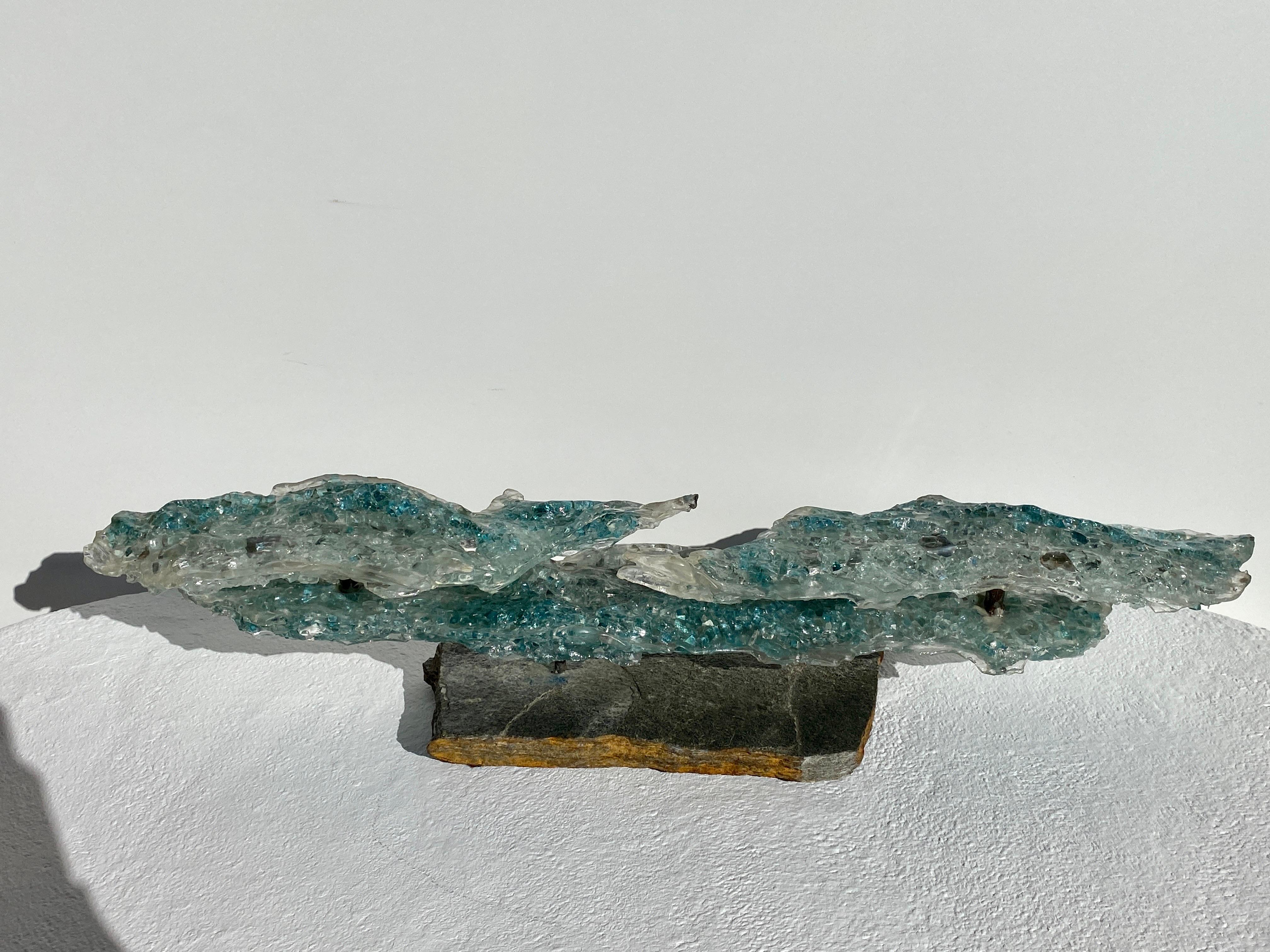 Brutalist desktop / tabletop glass sculpture.
It is made of crashed glass and mirror melted into clear acrylic and mounted on natural piece of slate.