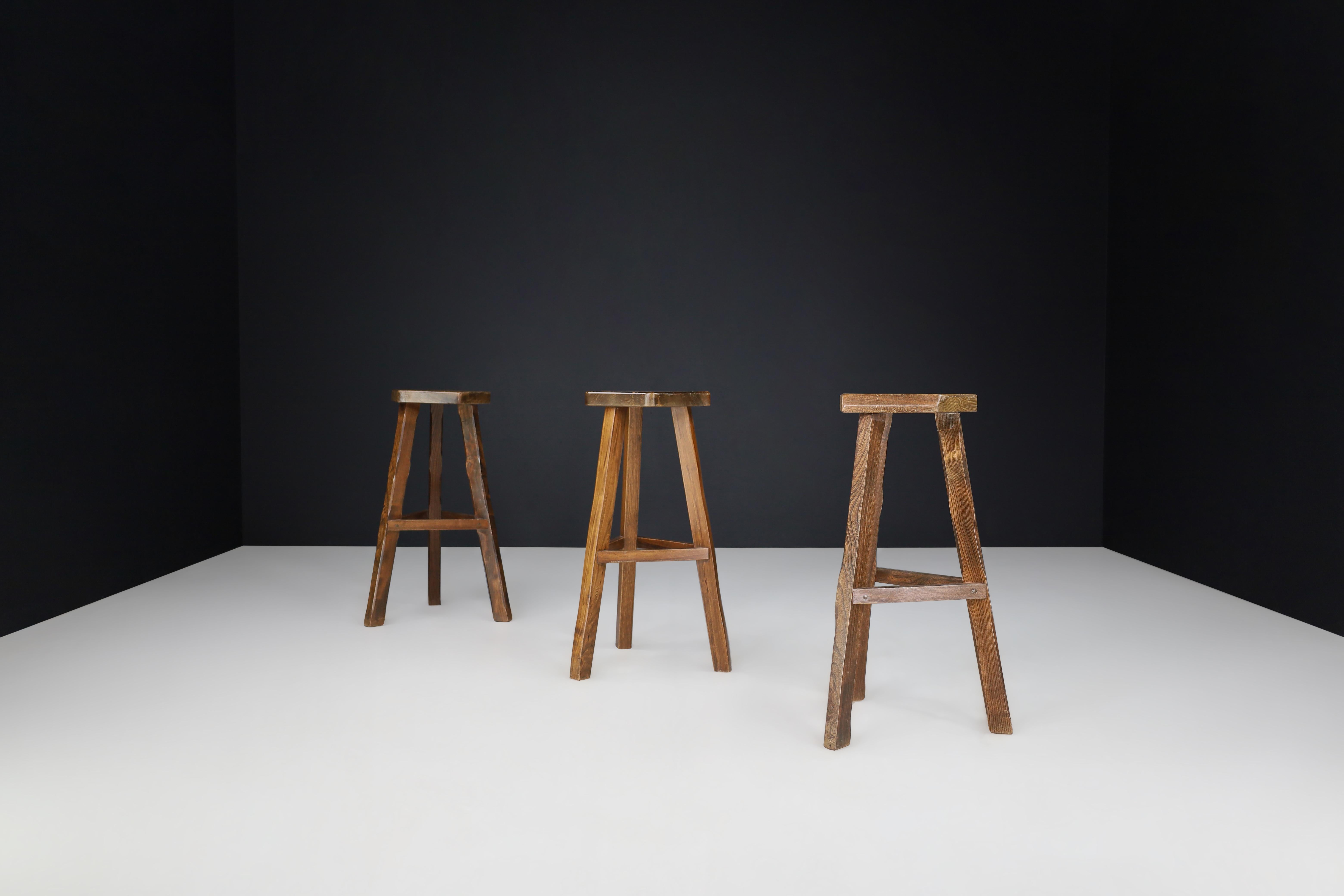 Olavi Hänninen Brutalist Elm Wood Bar Stools, Finland 1960s 

These set of 3 bar stools, crafted by Finnish designer Olavi Hänninen in the 1960s, boast unique warm tones due to their dark stained Elm wood construction. Hand-carved with precision,