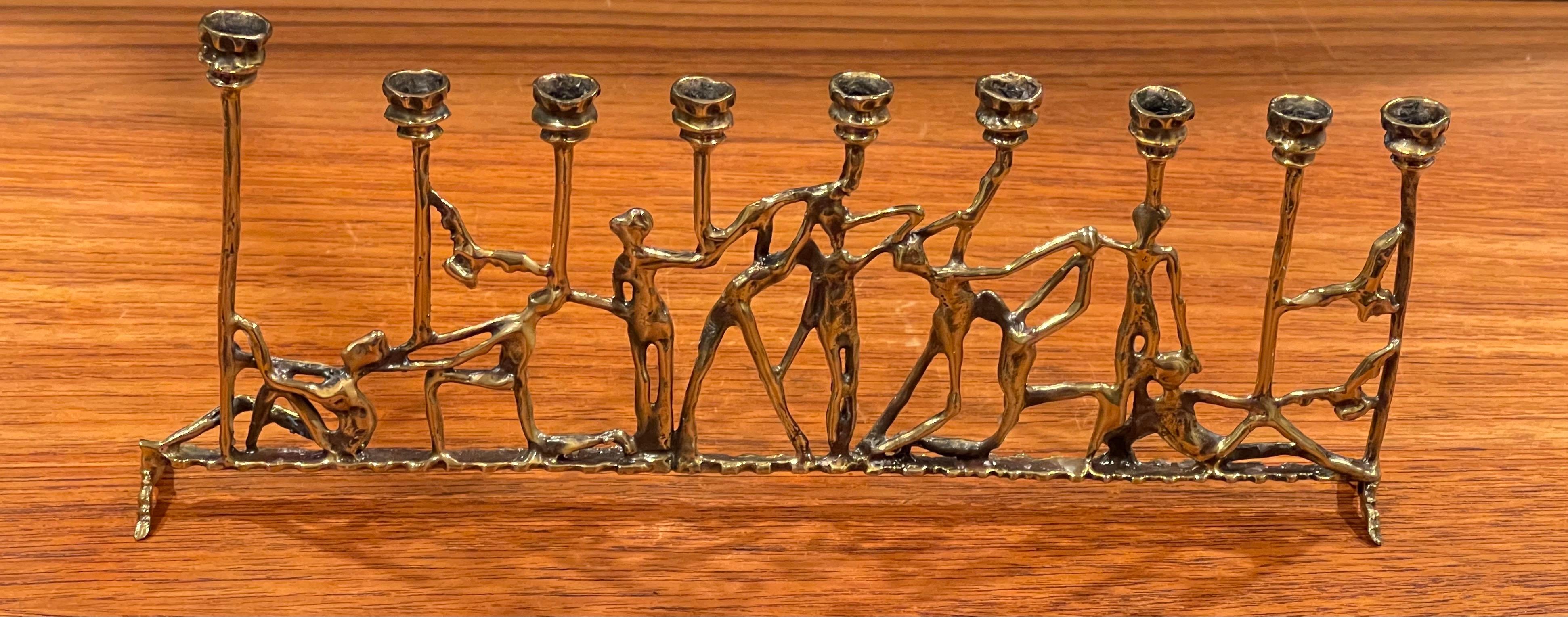 Brutalist figurative brass menorah in the style of Frederick Weinberg, circa 1970s. The piece measures 10.5