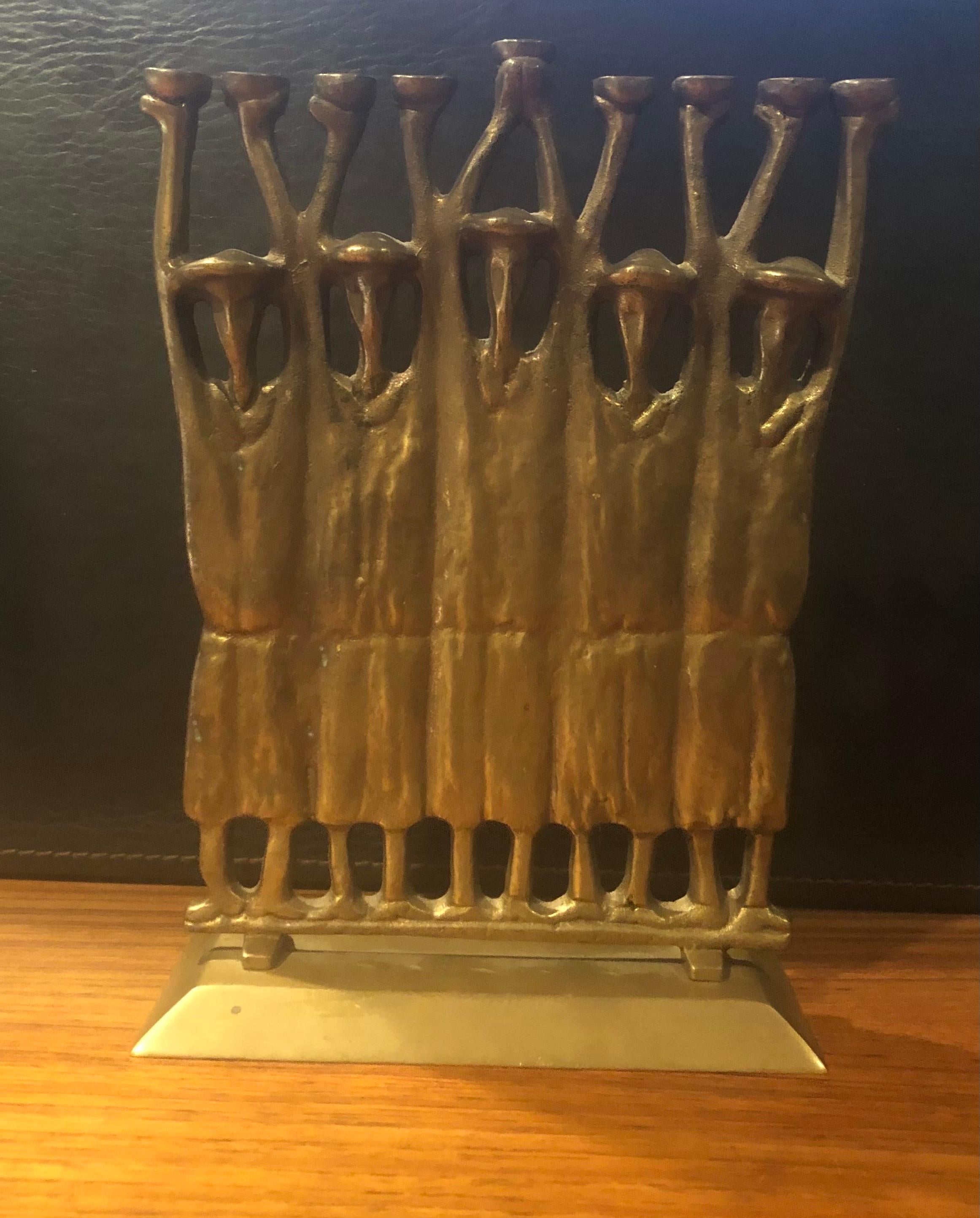 Brutalist figurative rabbi menorah in bronze by Ruth Bloch, circa 1970s. The menorah measures 7.5