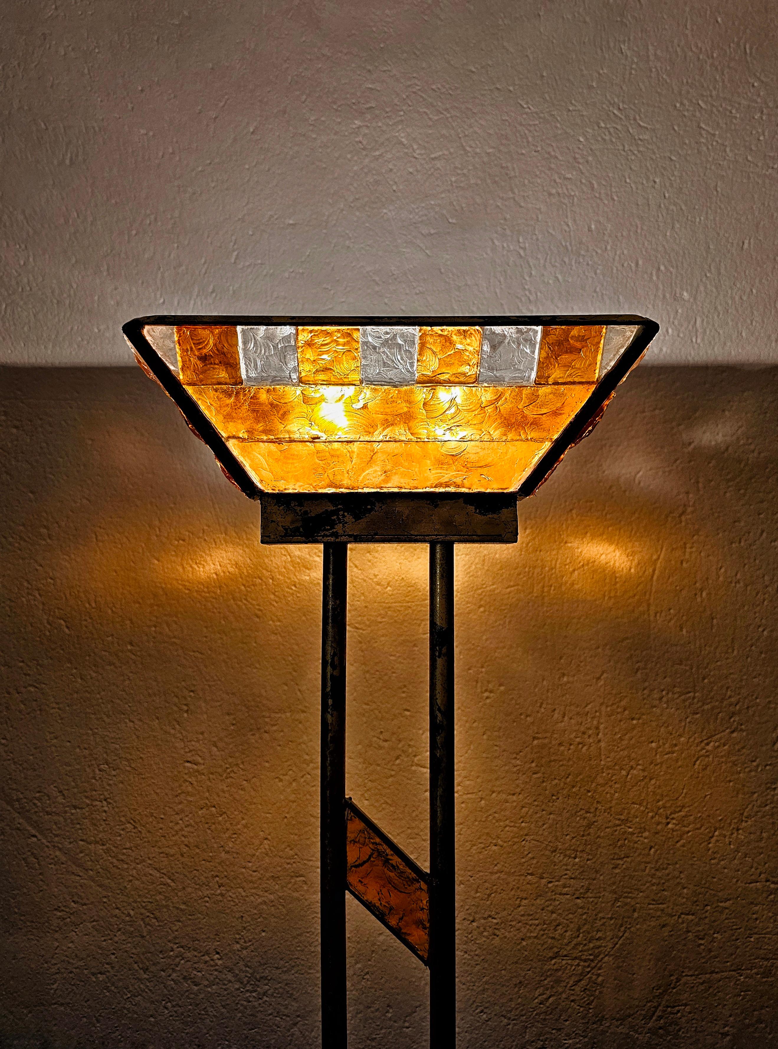En este anuncio encontrarás una lámpara de pie Brutalista excepcionalmente rara fabricada por Longobard. La lámpara tiene una llamativa pantalla de cristal de Murano martillado en ámbar y un hermoso soporte de hierro dorado en oro y verde. Fabricado
