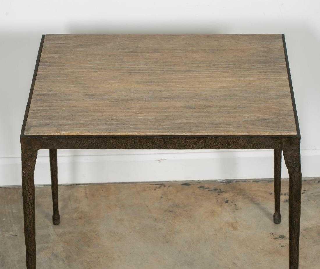 A Brutalist-style table with iron sculpted legs and light gray faux bois composite inset top. The light tonal composite top is in contrast to the roughly textured iron legs that taper to a delicate foot, and all are reminiscent of Paul Evans. The