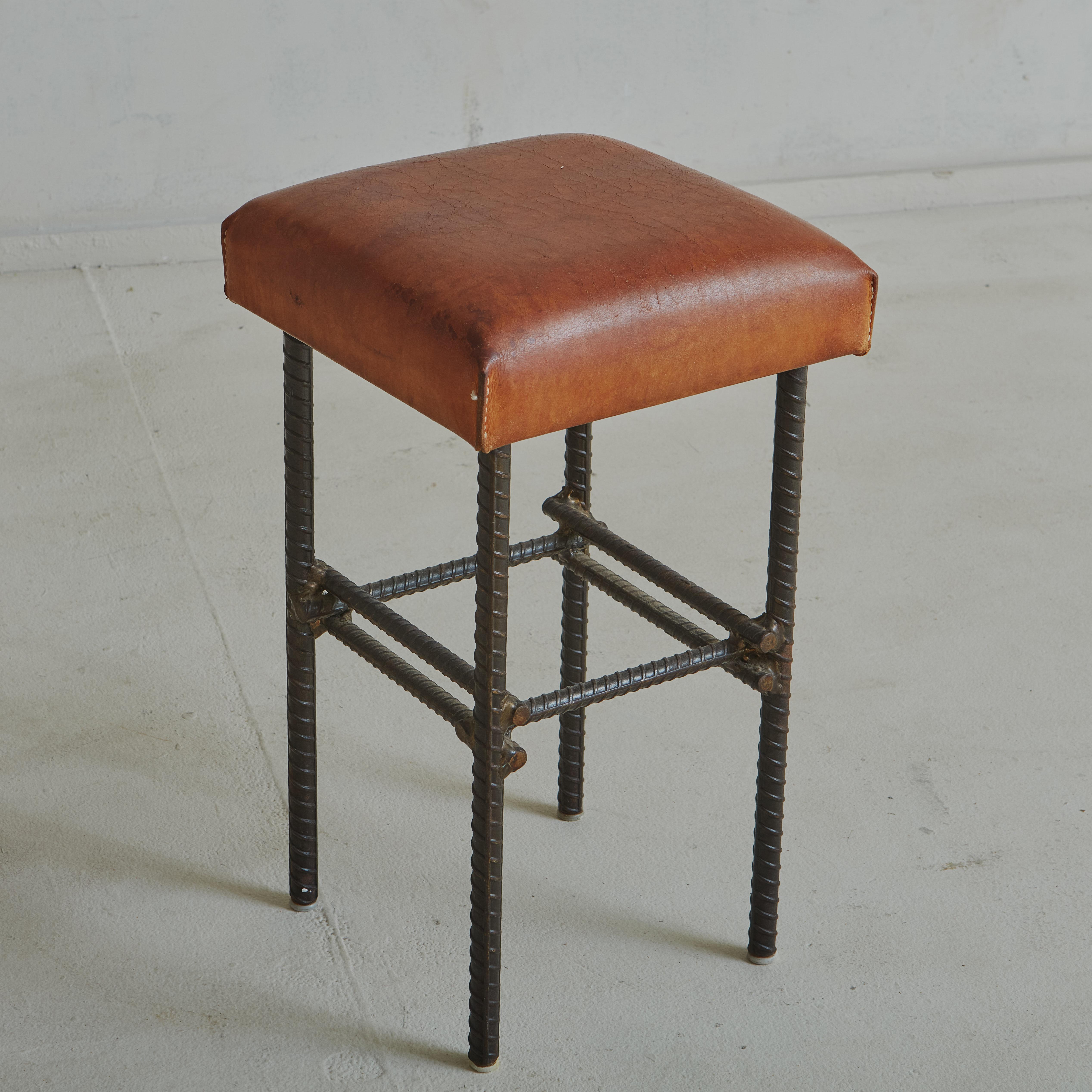 Beautiful brutalist stool with welded forged iron base and a brown leather seat featuring a gorgeous patina created by time.

Brutalism is an architectural current, born in the 1950s in England, seen as the overcoming of the Modern Movement in