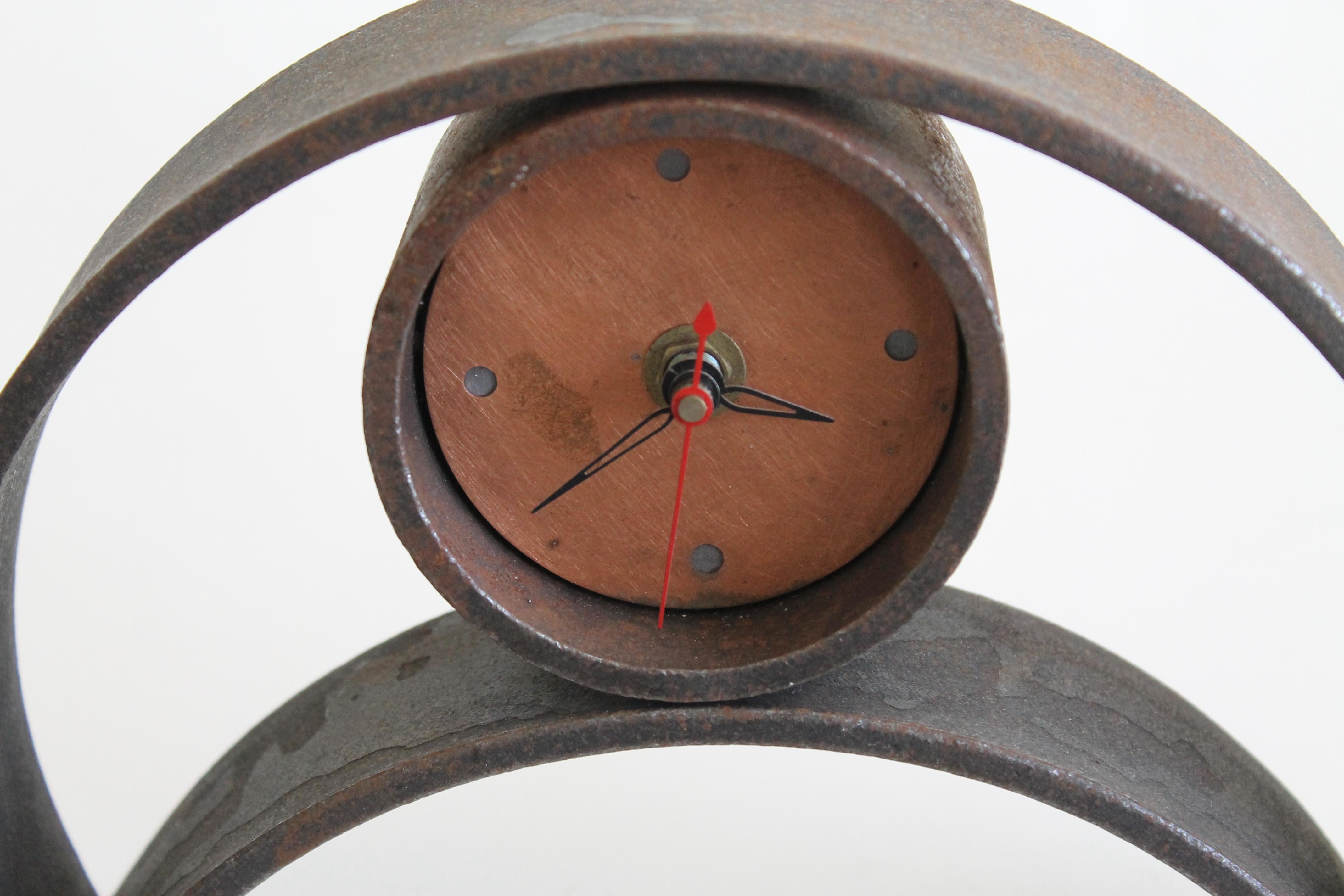 A heavy forged iron clock with copper face and brass numeral indicators. Circular center 