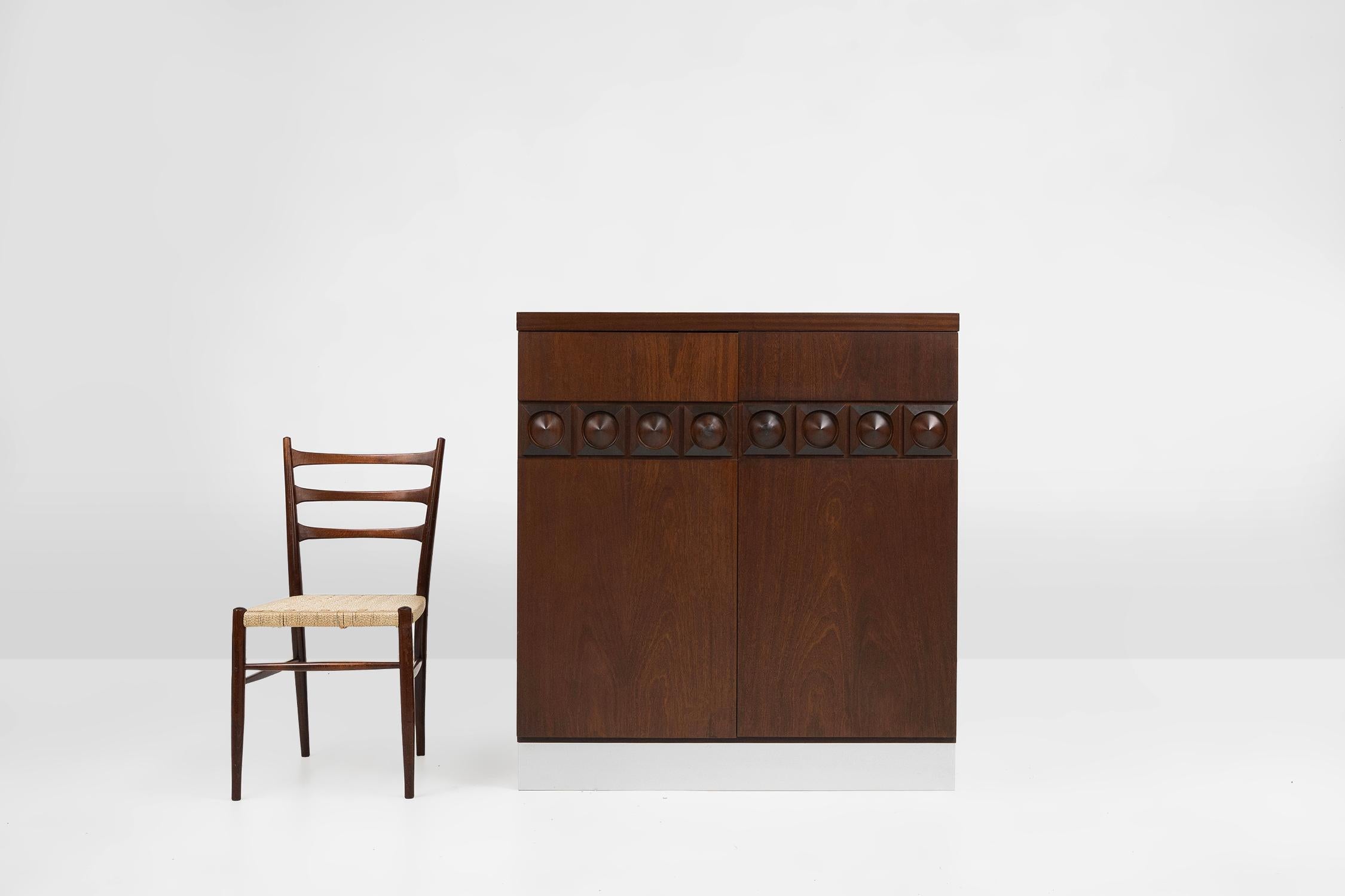 Belgium / 1970 / bar cabinet / wood and aluminium / brutalist / mid century / vintage 

Belgium brutalist wooden sideboard with two geometrical patterned doors and aluminium bottom. 
Behind the two doors the cabinet has several shelves and a bottle