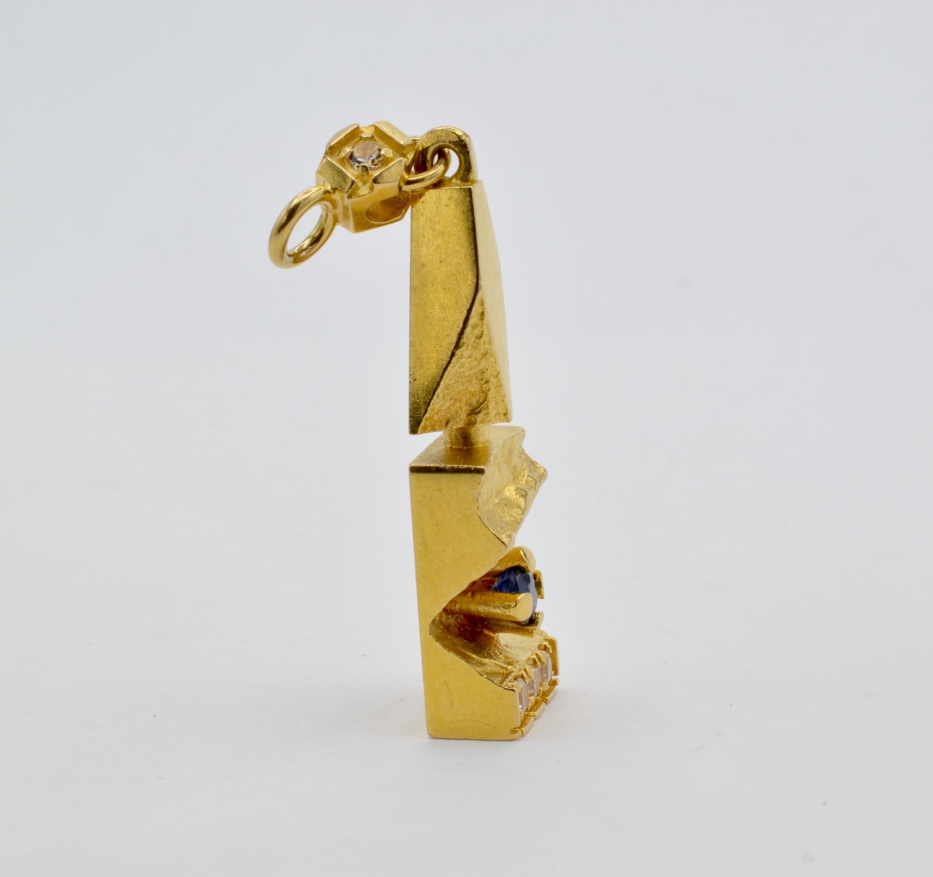 This 1950's vintage and substantial 18K yellow gold Brutalist pendant was made in Finland and is adorned with 4 diamonds (0.13 total carat weight) and a center sapphire (0.25 carats). The architectural design makes an artistic statement with