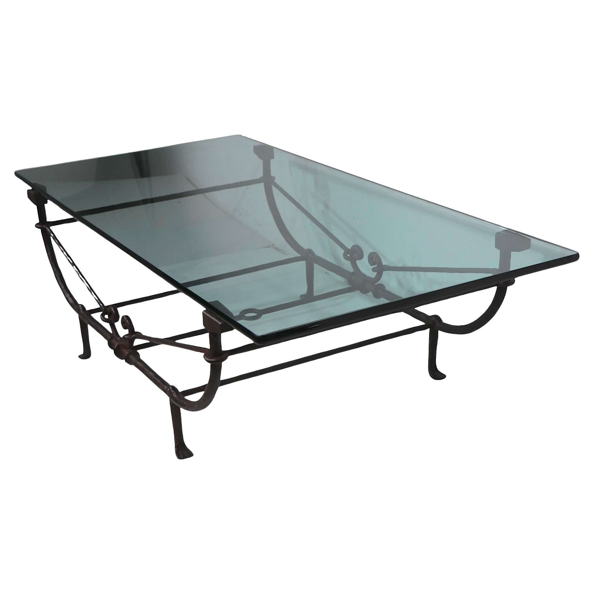 Exceptional iron and glass coffee table by Paul Ferrante, in the style of Giacometti, made in Italy circa 1970/80's. The table exhibits Brutalist, and Greco Roman Revival stylistic elements, it has a cast iron base and a thick tempered glass top -